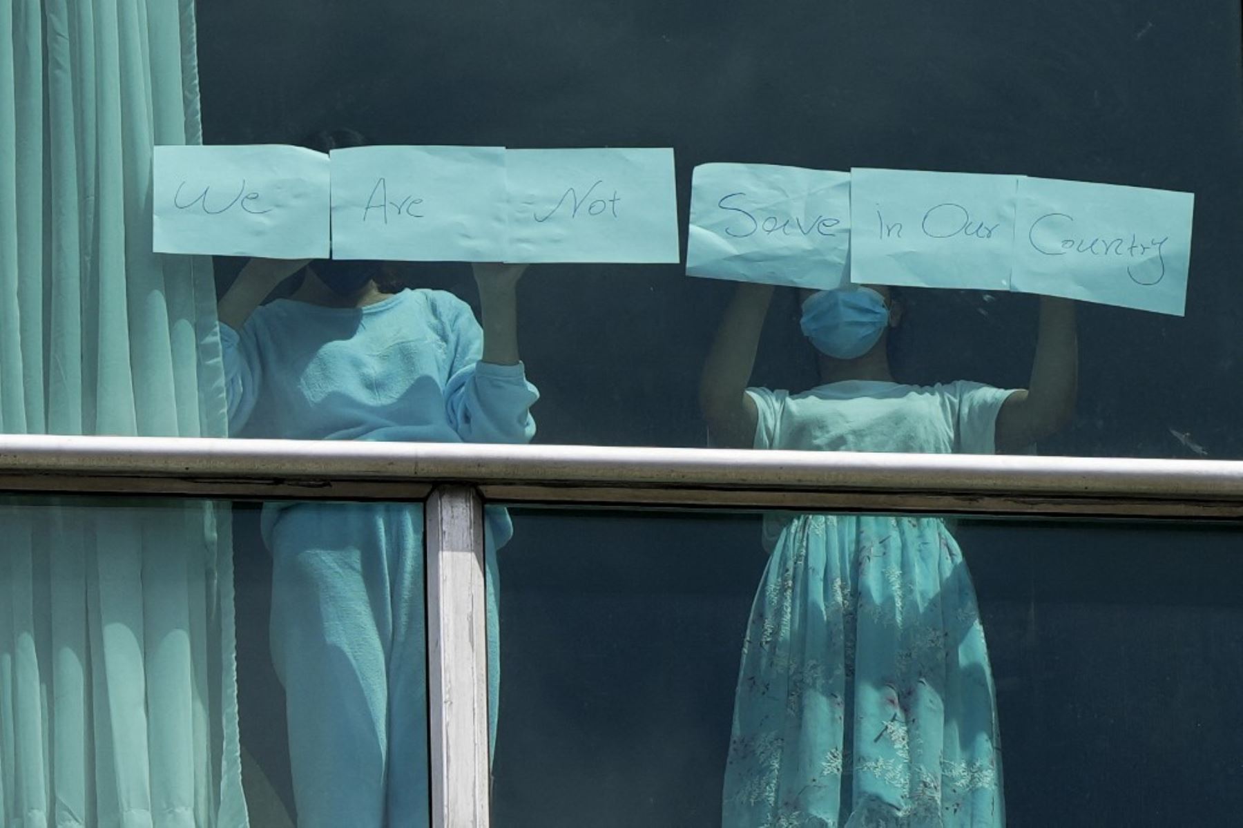 Los migrantes deportados de los Estados Unidos colocan papeles con un mensaje escrito en la ventana del Hotel Decapolis, donde se alojan temporalmente en la ciudad de Panamá, el 18 de febrero de 2025. (Foto de ARNULFO FRANCO / AFP)