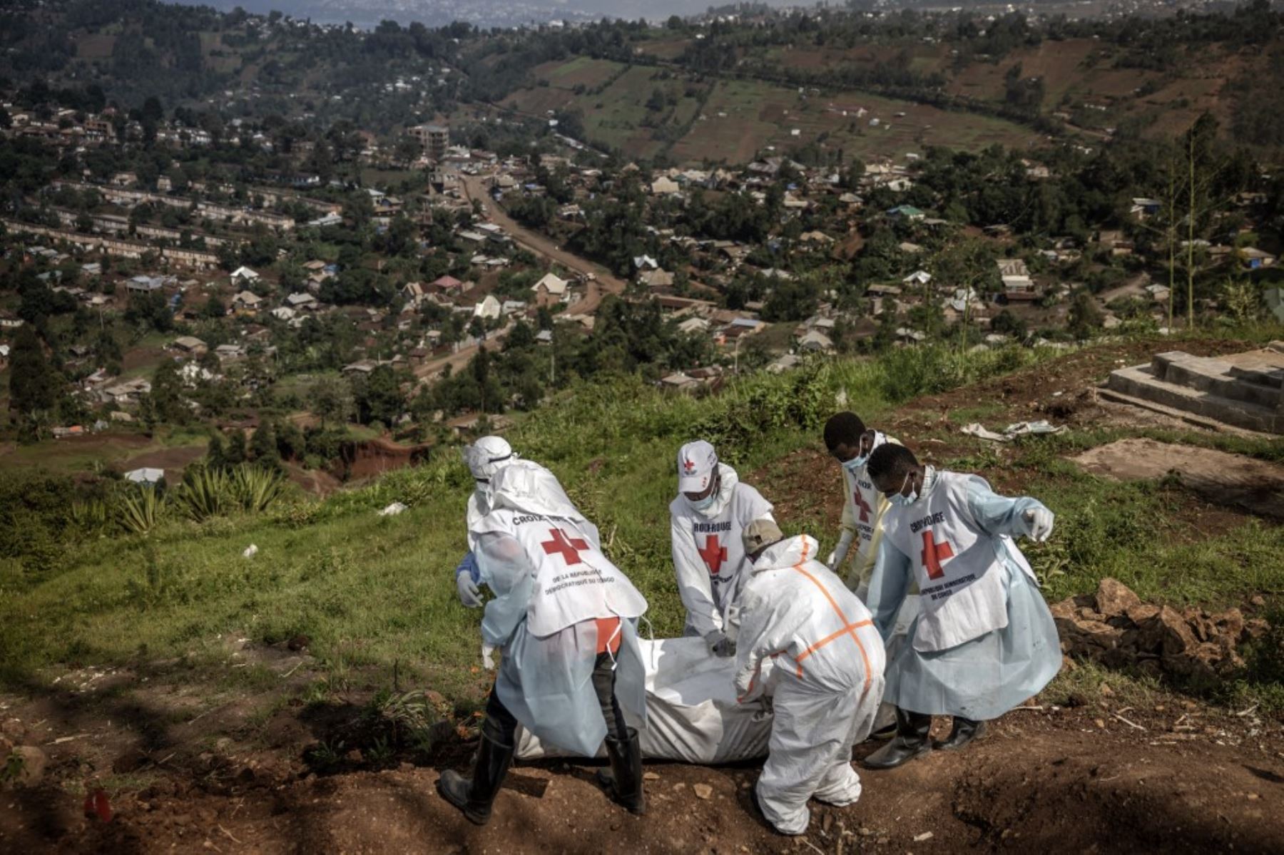 Miembros de la Cruz Roja Congoleña llevan bolsas de cadáveres que contienen restos humanos durante un entierro masivo para las víctimas de los enfrentamientos en el este de la República Democrática del Congo en el cementerio de Musigiko en Bukavu el 20 de febrero de 2025. (Foto de Luis TATO / AFP)