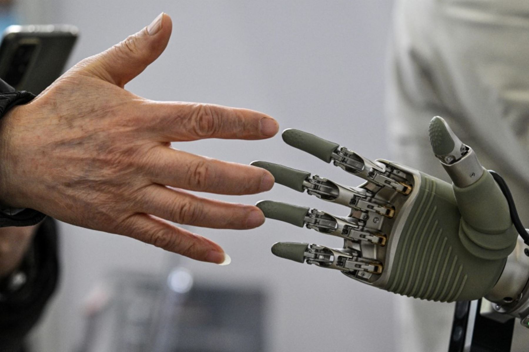 Un hombre toca una mano robótica de OY Motion durante la Conferencia Global de Desarrolladores, organizada por la Asociación de la Industria de IA de Shanghai, en Shanghai el 21 de febrero de 2025. (Foto de Héctor RETAMAL / AFP)