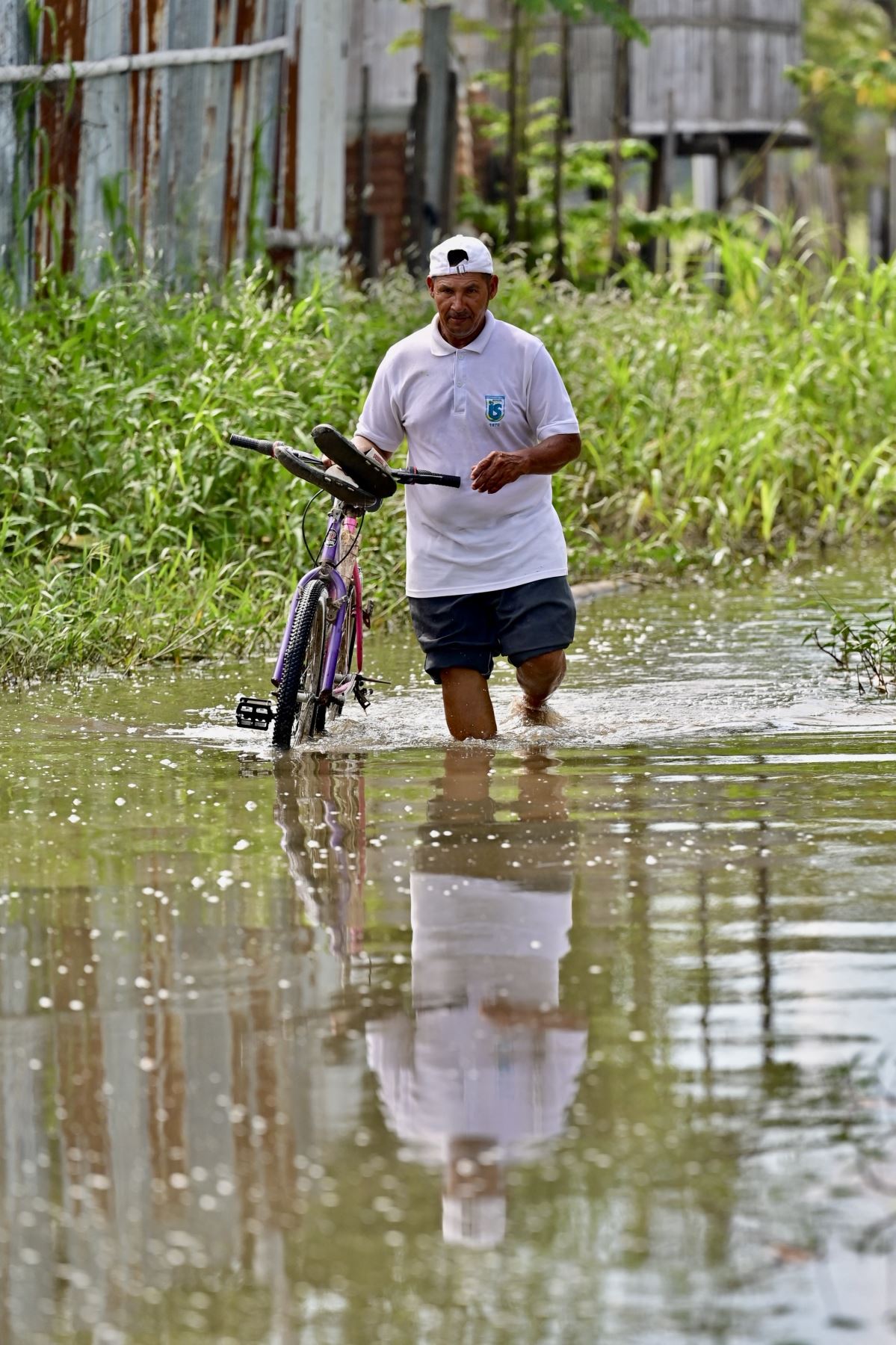 Un hombre camina por una calle inundada con su bicicleta en Yaguachi, Provincia del Guayas, Ecuador. AFP