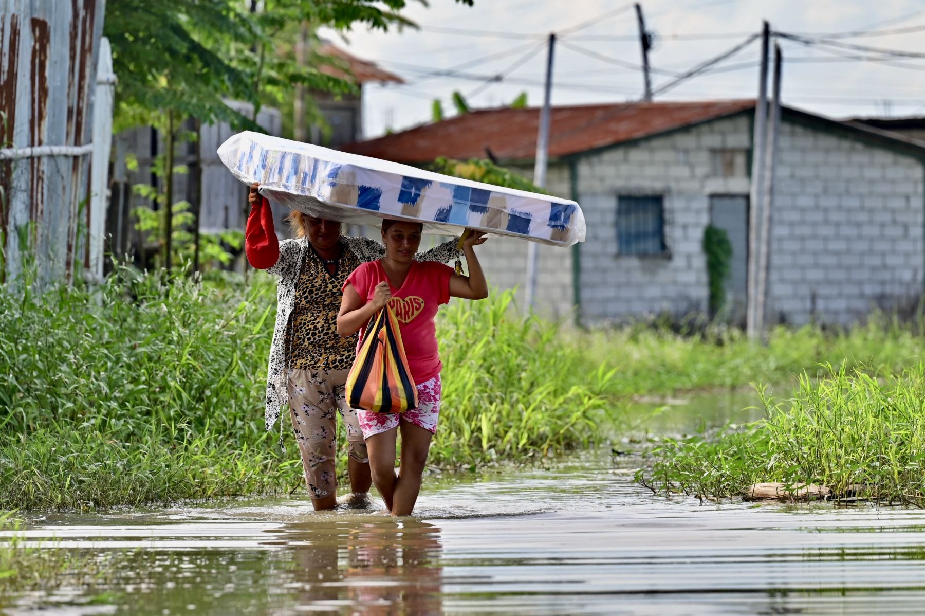 Mujeres cargan un colchón que recibieron  como ayuda tras ser afectadas por las inundaciones en Yaguachi, Provincia del Guayas, Ecuador. AFP