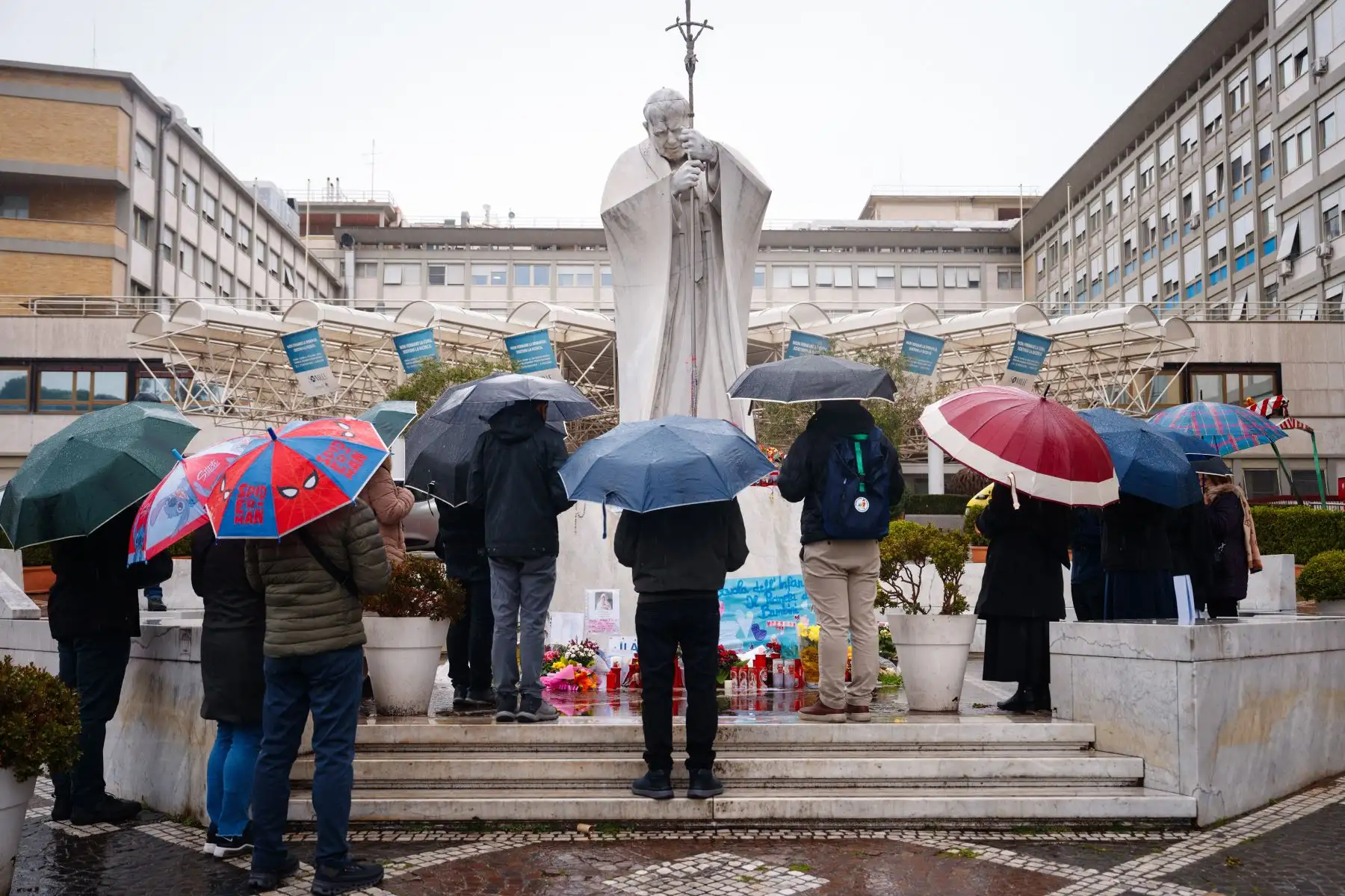 La gente reza bajo la lluvia ante la estatua de Juan Pablo II en el Hospital Universitario Gemelli, donde el Papa Francisco está hospitalizado con neumonía, en Roma.
Foto: AFP