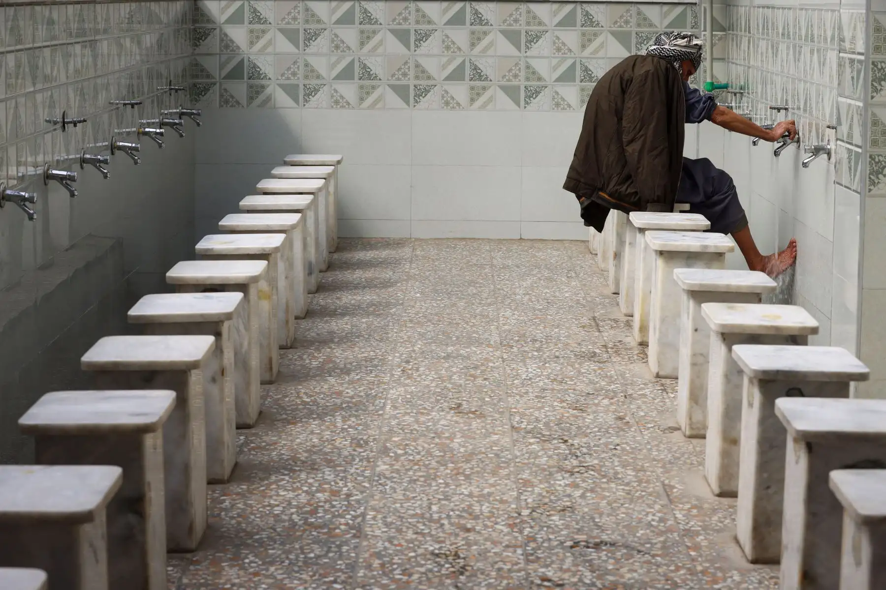 Un hombre realiza la ablución antes de rezar en el santuario del jeque sunita Abdul Qadir al-Jilani en Bagdad, durante el mes sagrado musulmán del Ramadán. AFP