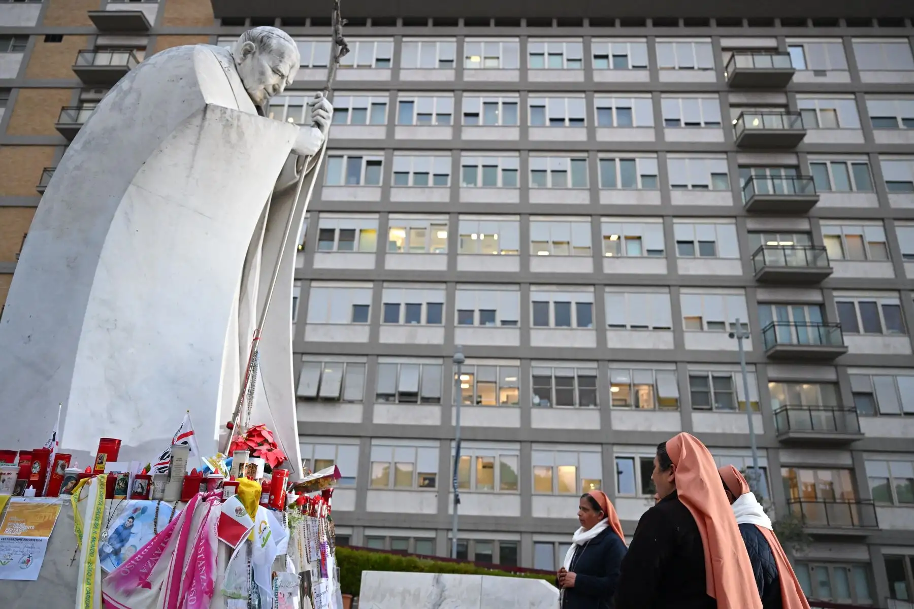 Las monjas rezan a los pies de una estatua de Juan Pablo II en el Hospital Gemelli, donde está internado el papa Francisco, El papa Francisco pasó una noche tranquila en el hospital, mientras el líder de la Iglesia católica de 88 años lucha contra una neumonía. 
Foto. ANDINA/AFP