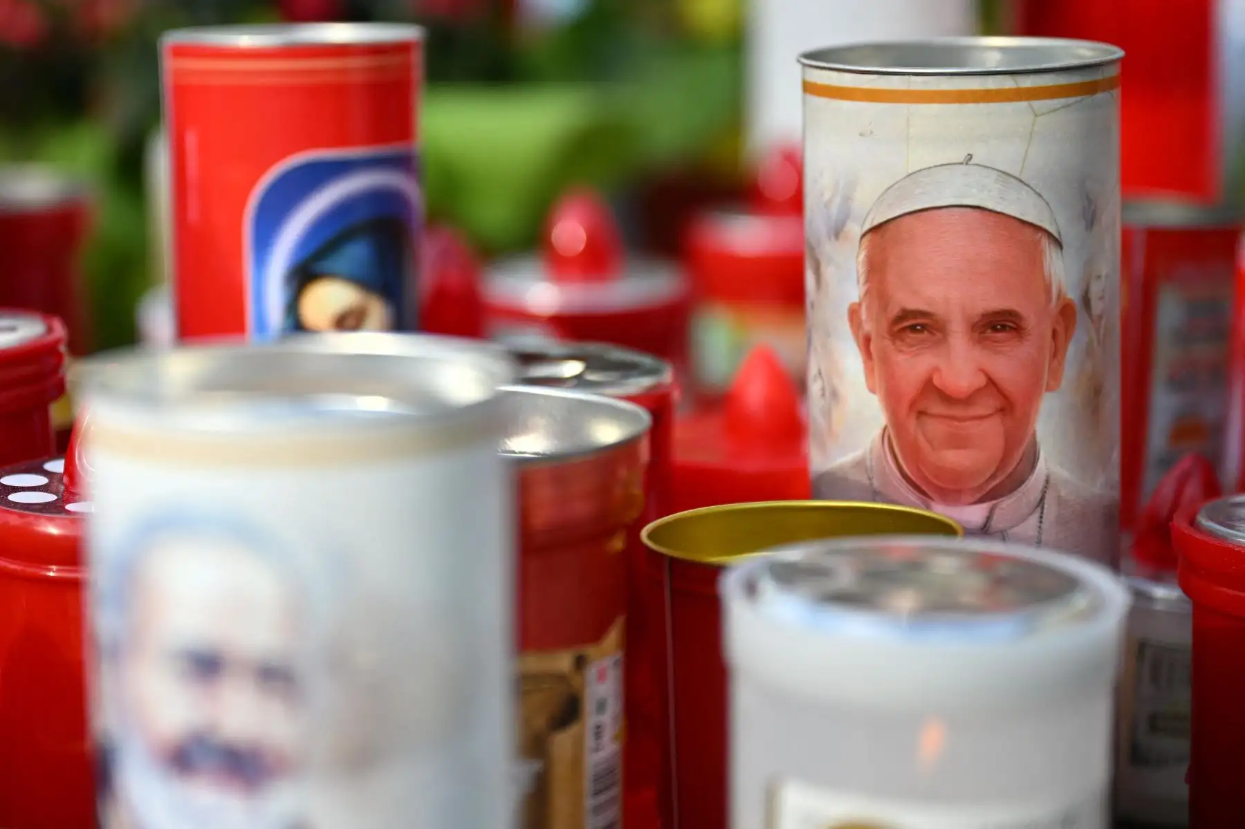 Una vela con el retrato del papa Francisco se coloca a los pies de una estatua de Juan Pablo II en el exterior del hospital Gemelli, donde el papa Francisco está internado en Roma. El papa Francisco pasó una noche tranquila en el hospital, mientras el líder de la Iglesia católica de 88 años lucha contra la neumonía. Foto: ANDINA/AFP