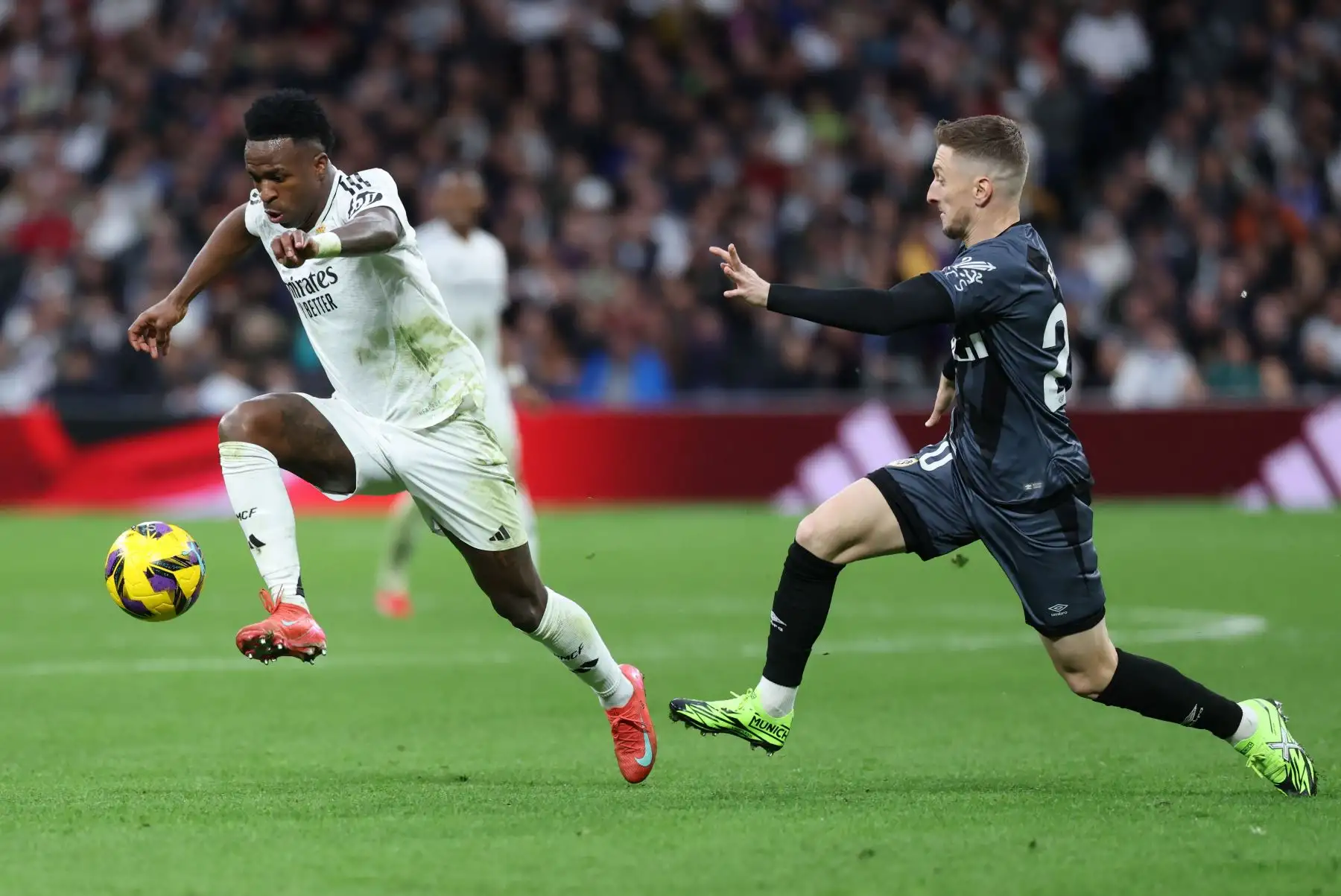 El delantero brasileño del Real Madrid Vinicius Junior es desafiado por el defensor albanés del Rayo Vallecano Ivan Balliu Campeny durante el partido de fútbol de la liga española entre el Real Madrid CF y el Rayo Vallecano de Madrid. Foto: ANDINA/AFP