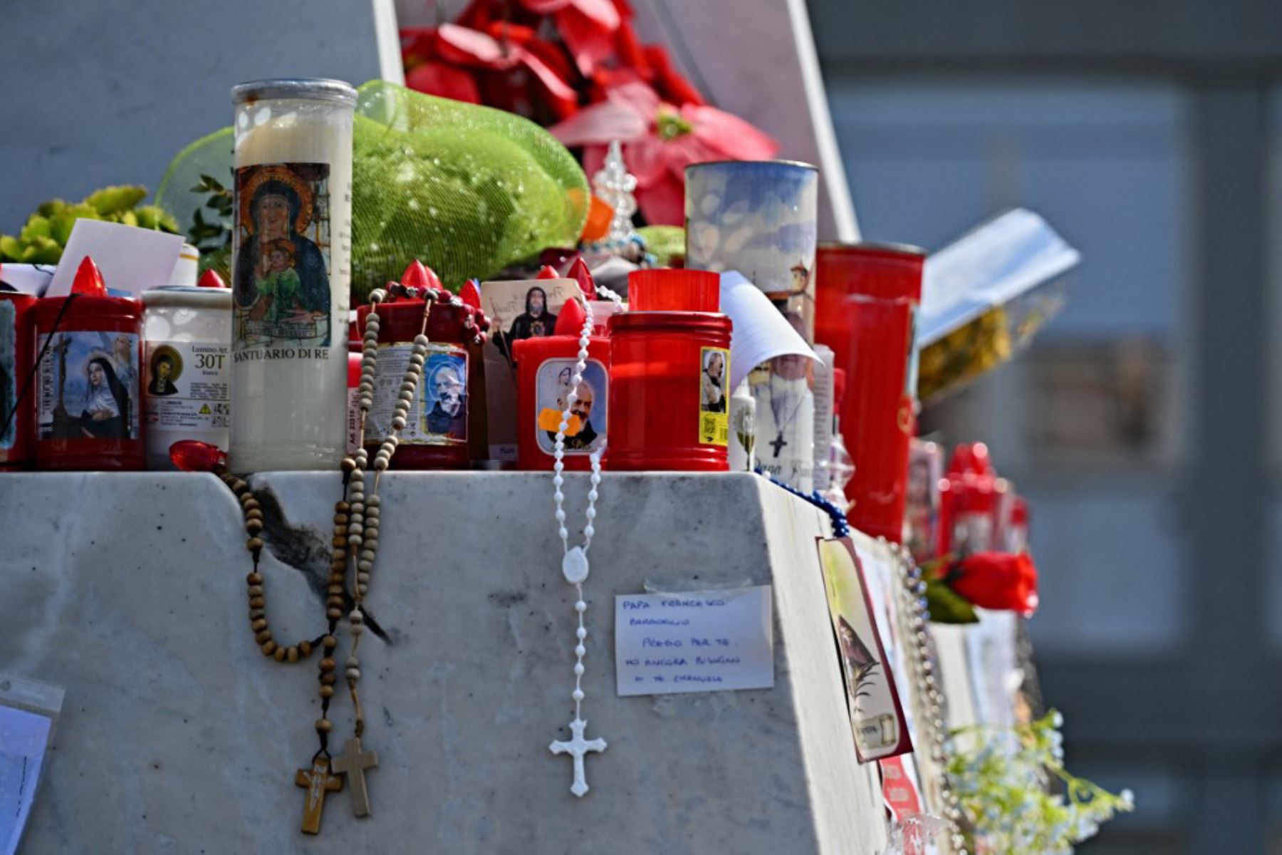 Se colocan velas y rosarios ante la estatua de Juan Pablo II en el exterior del Hospital Universitario Gemelli, donde el Papa Francisco está hospitalizado con neumonía, en Roma. Foto: AFP