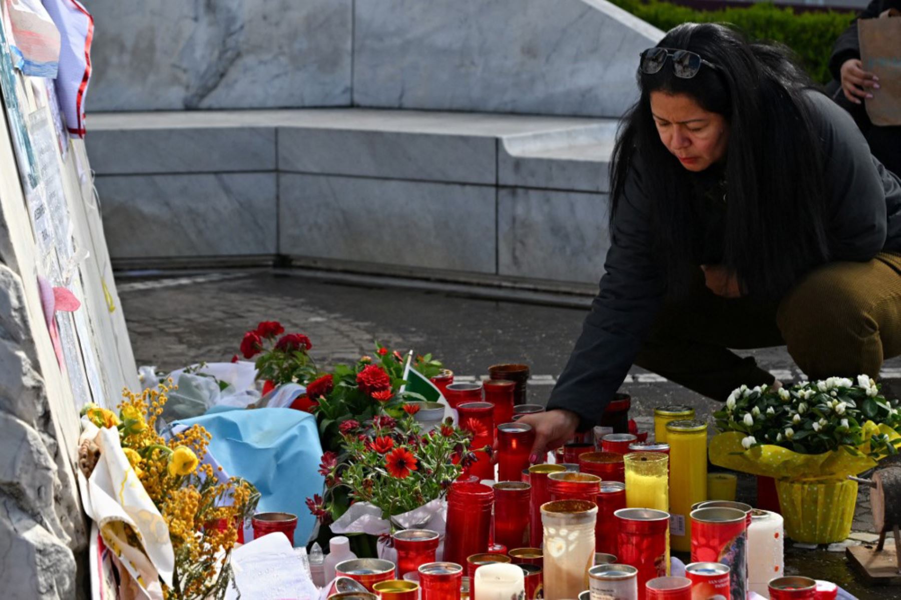 Una mujer coloca una vela en la estatua de Juan Pablo II afuera del Hospital Universitario Gemelli, donde el Papa Francisco está hospitalizado con neumonía, en Roma. Foto: AFP