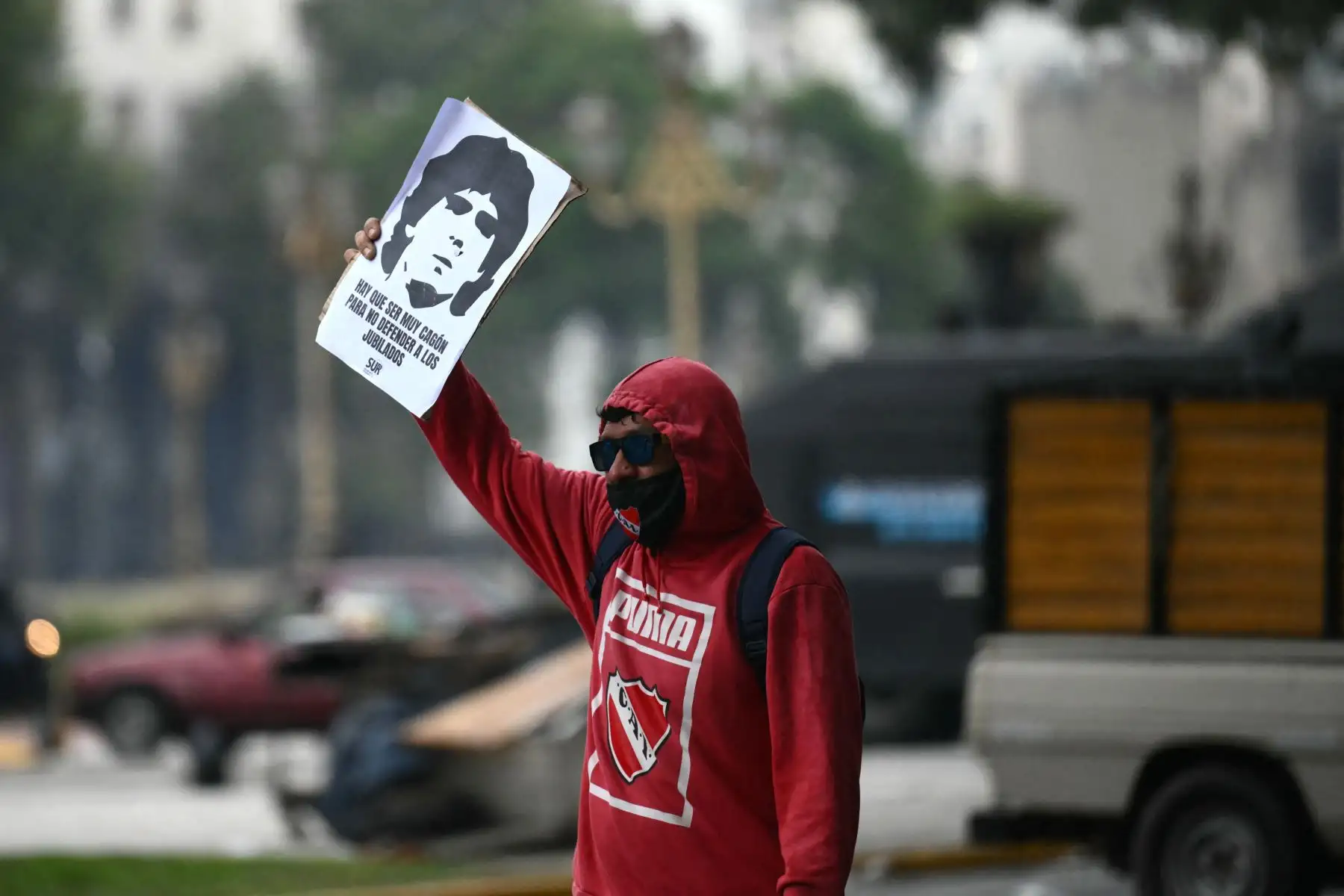 Un manifestante sostiene un cartel que representa al fallecido futbolista argentino Diego Maradona durante una protesta de jubilados apoyados por aficionados al fútbol contra el gobierno del presidente Javier Milei en Buenos Aires. AFP