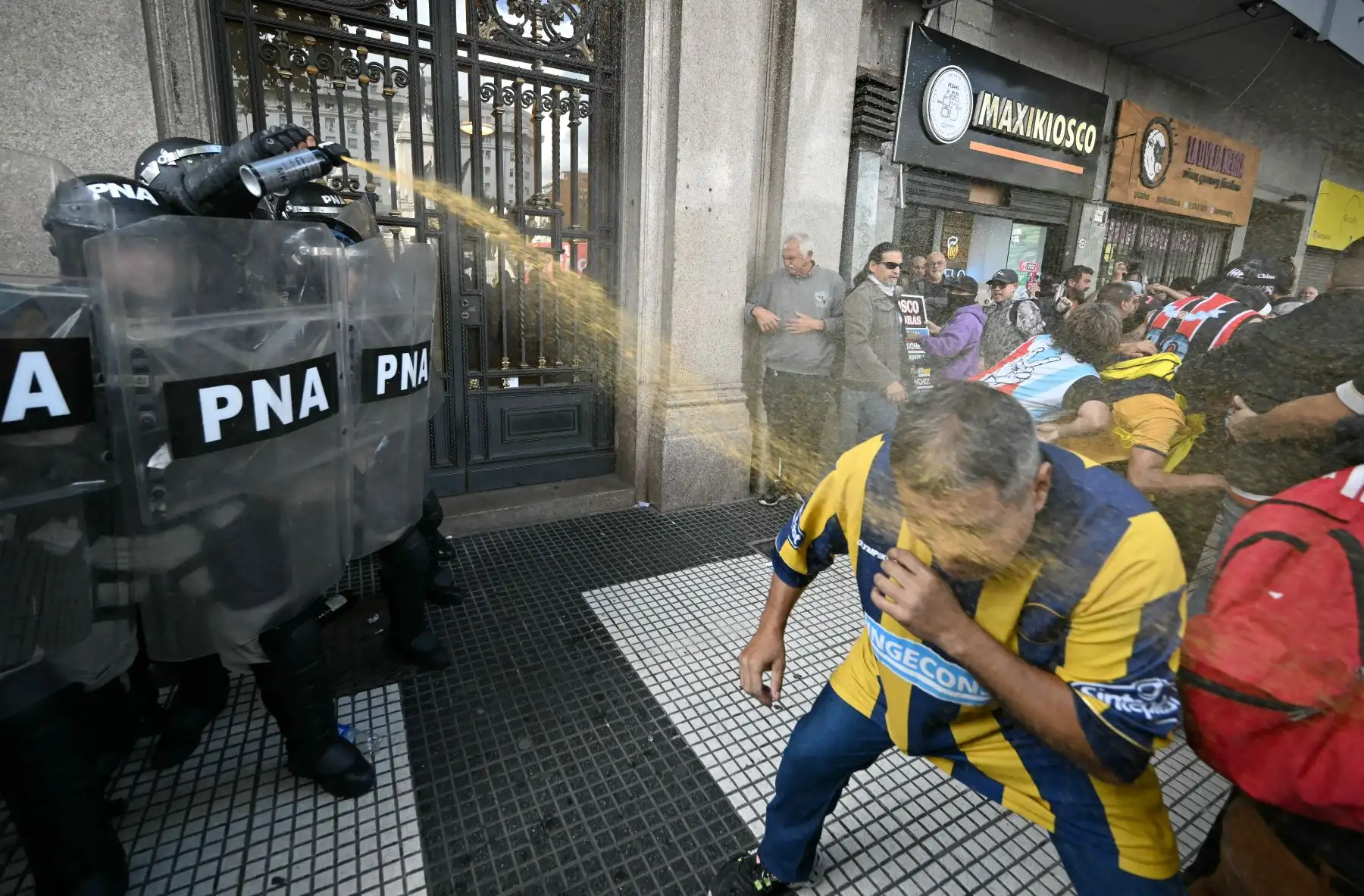 Un policía aplica gas pimienta a un seguidor de Rosario Central durante una protesta de jubilados apoyados por hinchas de fútbol contra el gobierno del presidente Javier Milei en Buenos Aires. AFP