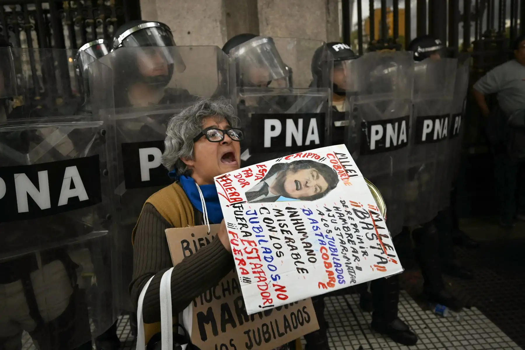 Una mujer grita consignas frente a la policía durante una protesta de jubilados apoyados por aficionados al fútbol contra el gobierno del presidente Javier Milei en Buenos Aires. AFP