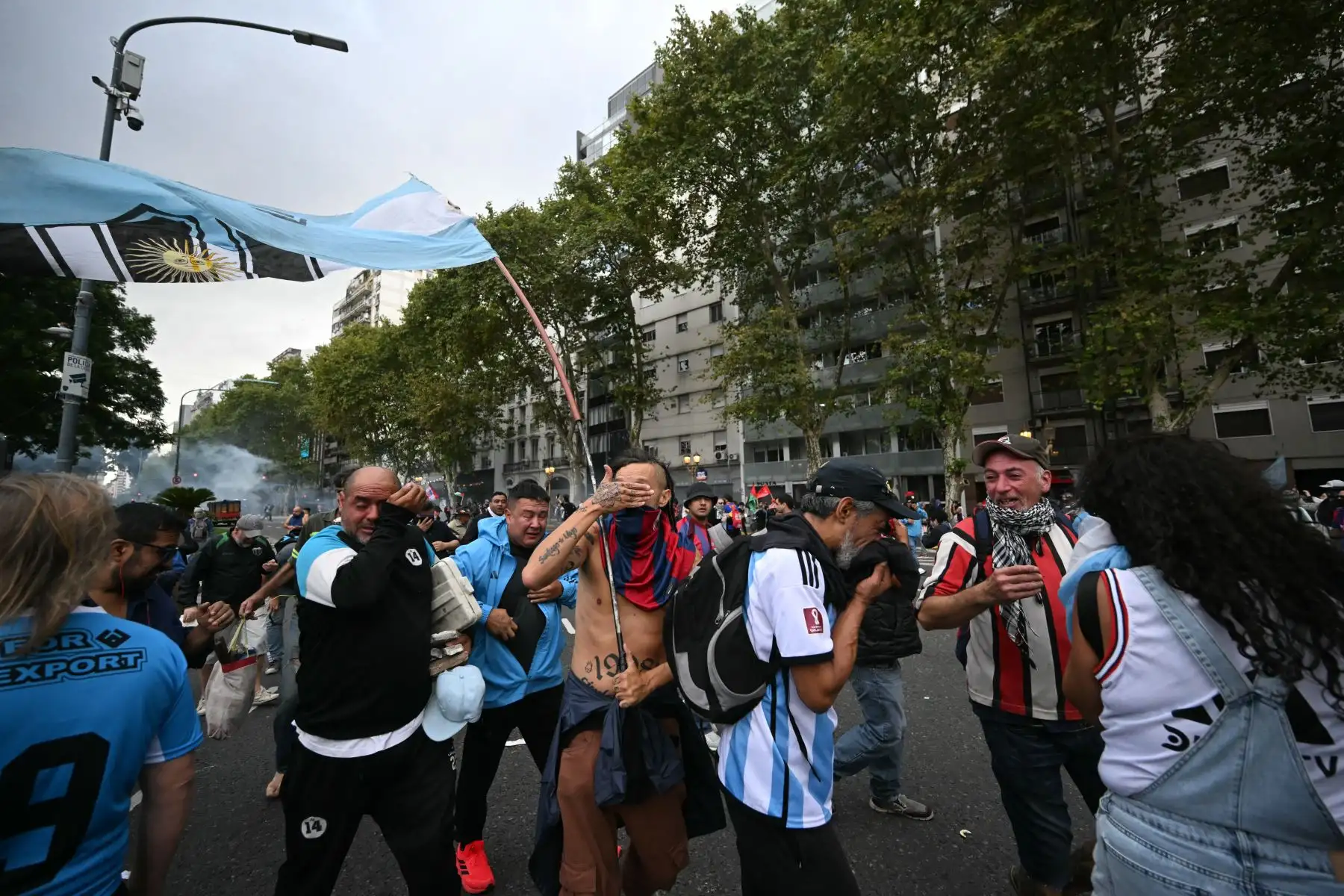 Los manifestantes se protegen de los gases lacrimógenos durante una protesta de jubilados apoyados por aficionados al fútbol contra el gobierno del presidente Javier Milei en Buenos Aires. AFP