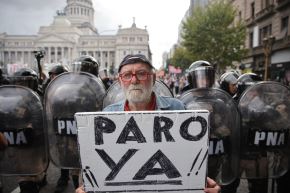 Un manifestante sostiene un cartel que dice en español "¡Huelga AHORA!" frente a agentes de la policía antidisturbios durante una protesta de jubilados apoyados por aficionados al fútbol contra el gobierno del presidente Javier Milei en Buenos Aires. AFP