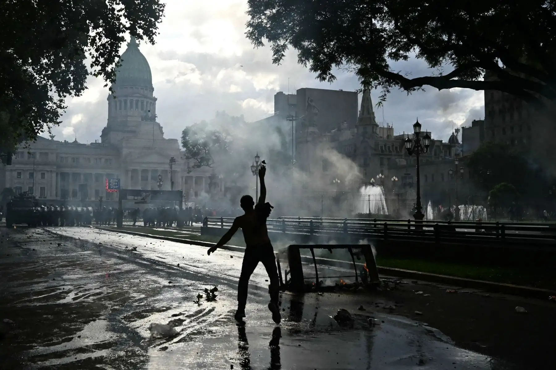 Un manifestante lanza una piedra mientras se enfrenta a la policía antidisturbios durante una protesta de jubilados apoyados por aficionados al fútbol contra el gobierno del presidente Javier Milei en Buenos Aires. AFP