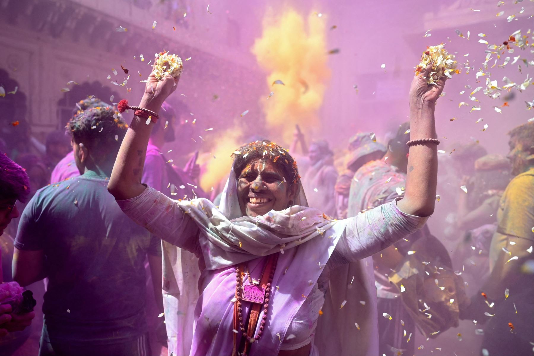 Una viuda untada con gulal (polvo de color), arroja pétalos de flores mientras celebra Holi, el festival hindú de colores de primavera, en un templo de Vrindavan. AFP