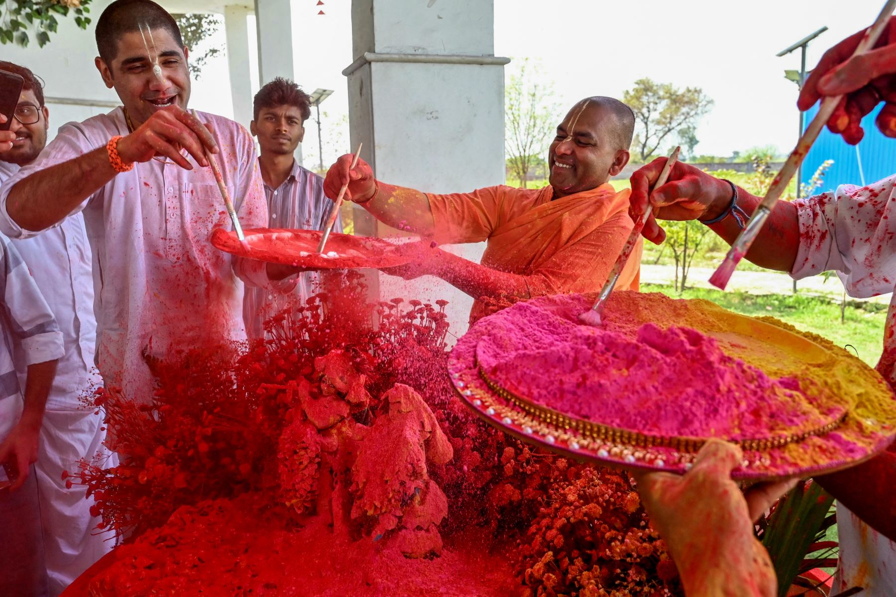 Sacerdotes hindúes y devotos de la Sociedad Internacional para la Conciencia de Krishna (ISKCON) bañan con colores los ídolos de las deidades Krishna y Radha durante la celebración de Holi, el festival hindú de colores de primavera, en un templo en las afueras de Amritsar. AFP