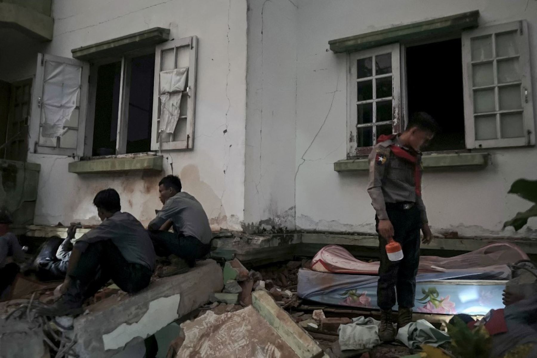 Un policía de Myanmar  ilumina con una linterna un edificio dañado en Naipyidó el 28 de marzo de 2025, tras un terremoto en el centro de Myanmar. Un potente terremoto sacudió Myanmar deformando las carreteras de la capital, Naipyidó, dañando edificios y obligando a la gente a huir a las calles en la vecina Tailandia. Foto: AFP