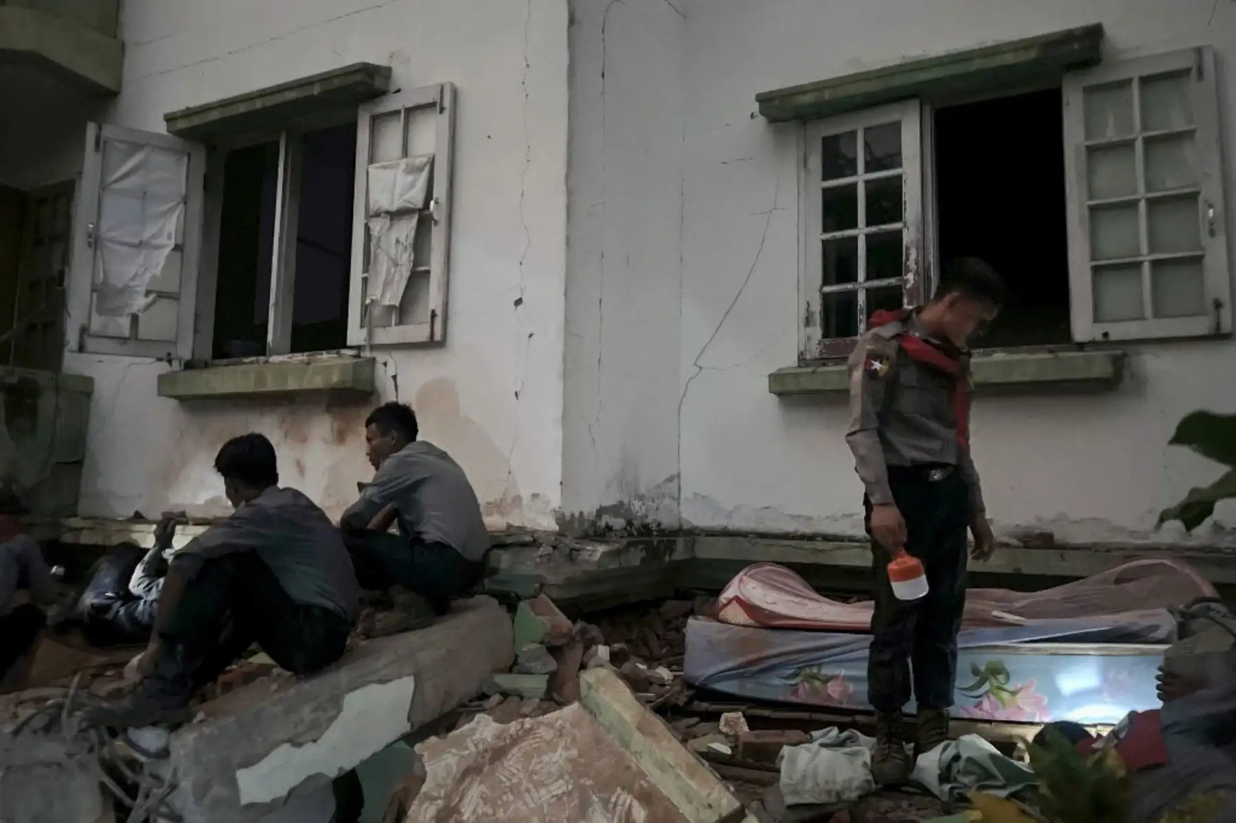 Un policía de Myanmar  ilumina con una linterna un edificio dañado en Naipyidó el 28 de marzo de 2025, tras un terremoto en el centro de Myanmar. Un potente terremoto sacudió Myanmar deformando las carreteras de la capital, Naipyidó, dañando edificios y obligando a la gente a huir a las calles en la vecina Tailandia. Foto: AFP