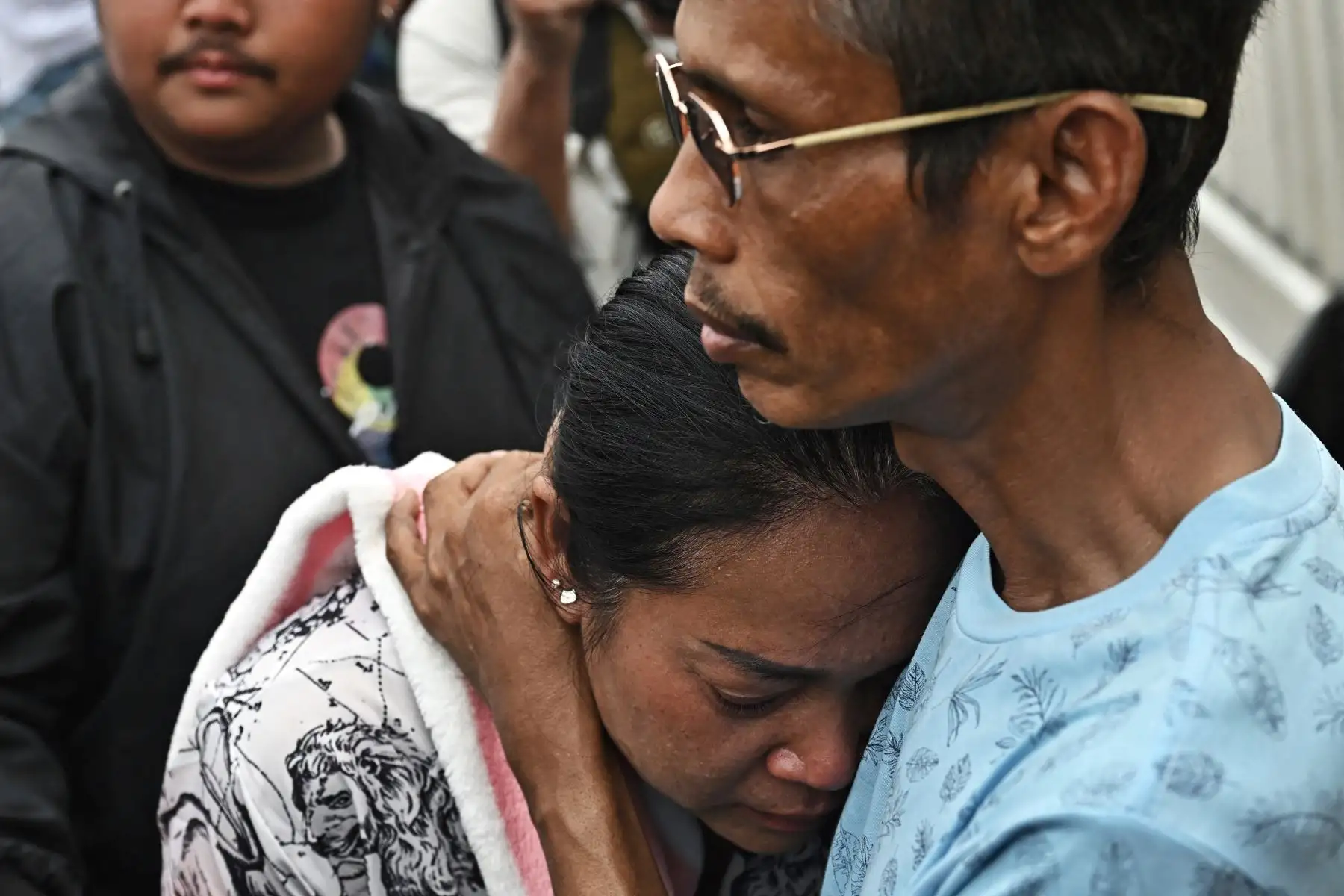 Naruemol Thonglek  recibe el abrazo de un amigo mientras esperan noticias de sus familiares desaparecidos en el lugar del derrumbe de un edificio en construcción en Bangkok.
Foto: AFP