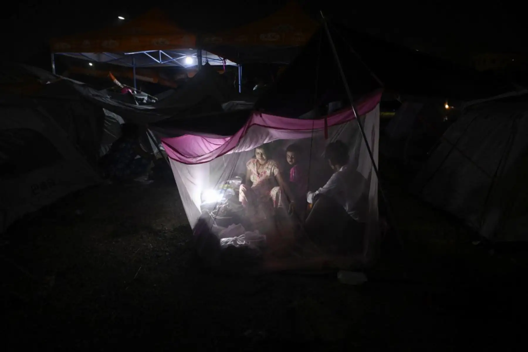 Personas se refugian en tiendas de campaña temporales instaladas al aire libre en Mandalay. Foto: AFP