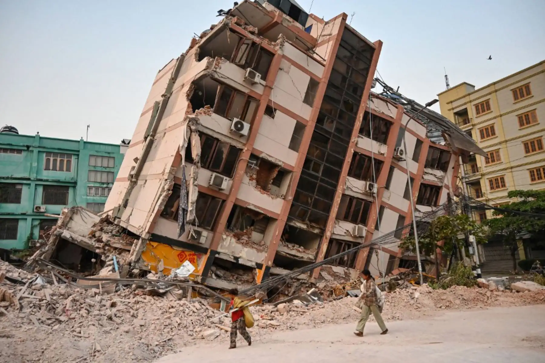 Niños pasan junto a un edificio derrumbado en Mandalay el 2 de abril de 2025, cinco días después de que un gran terremoto azotara el centro de Myanmar. Foto: AFP
