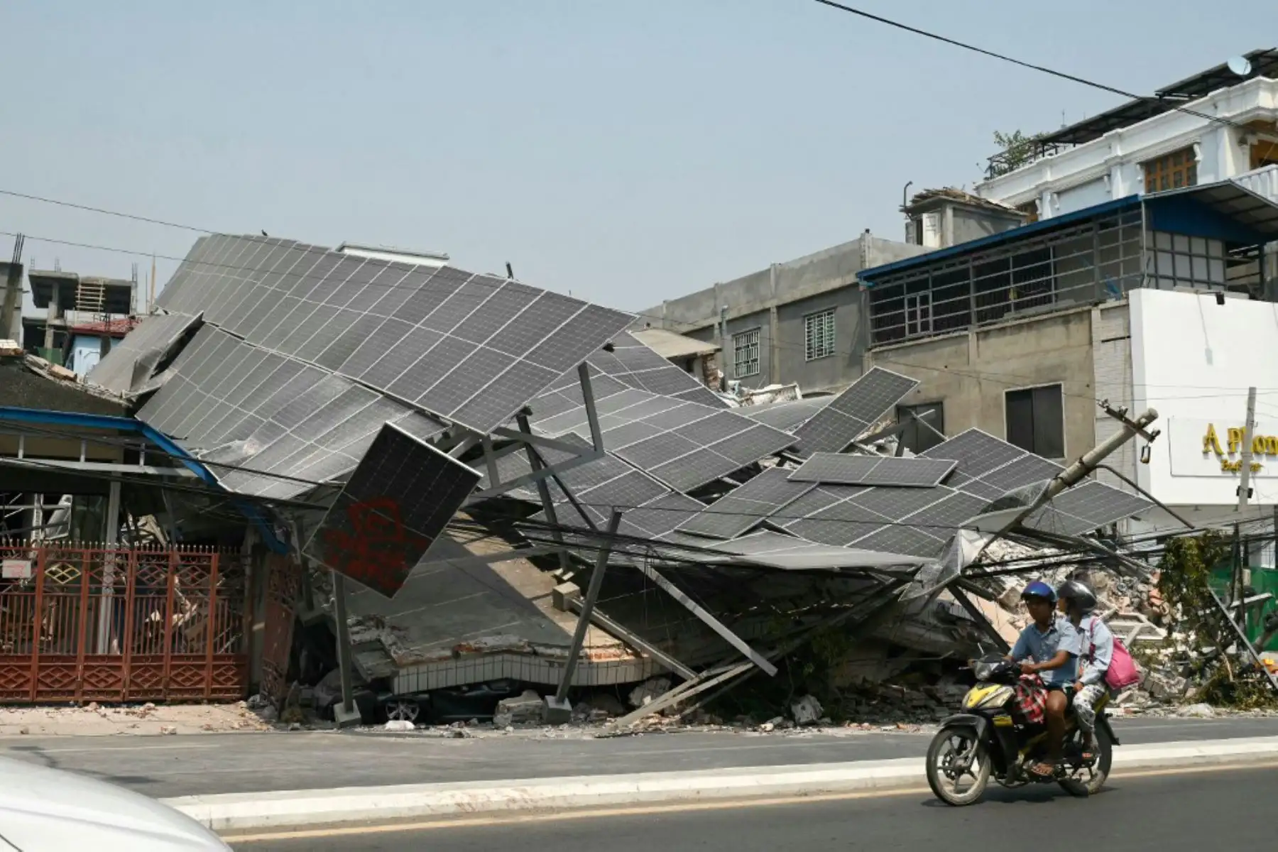 Personas en motocicleta pasan junto a un edificio derrumbado en Mandalay el 2 de abril de 2025, cinco días después de que un gran terremoto azotara el centro de Myanmar. Foto: AFP
