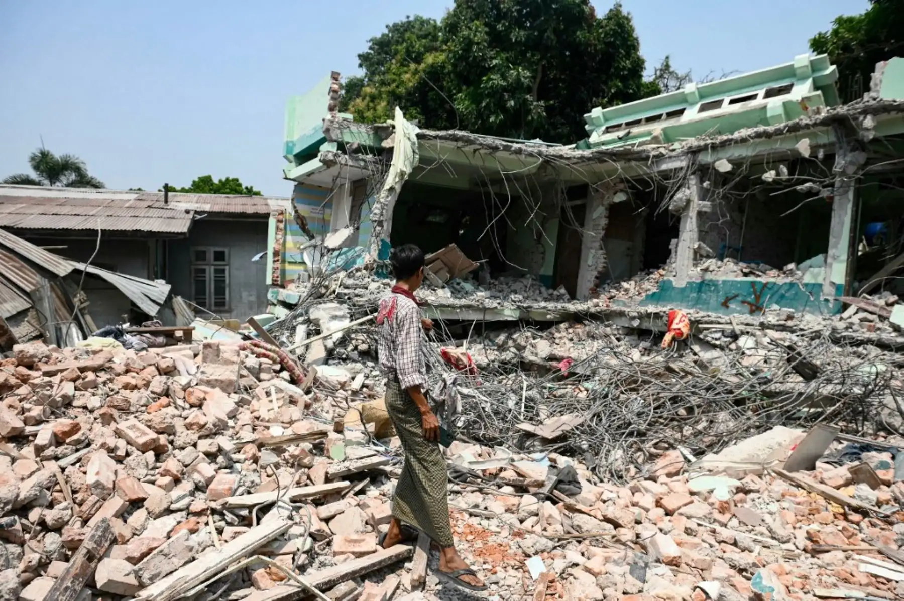 Un hombre permanece de pie sobre las ruinas de un hotel donde fue rescatado el sobreviviente Tin Maung Htwe en Sagaing el 3 de abril de 2025, tras el terremoto del 28 de marzo. Foto: AFP