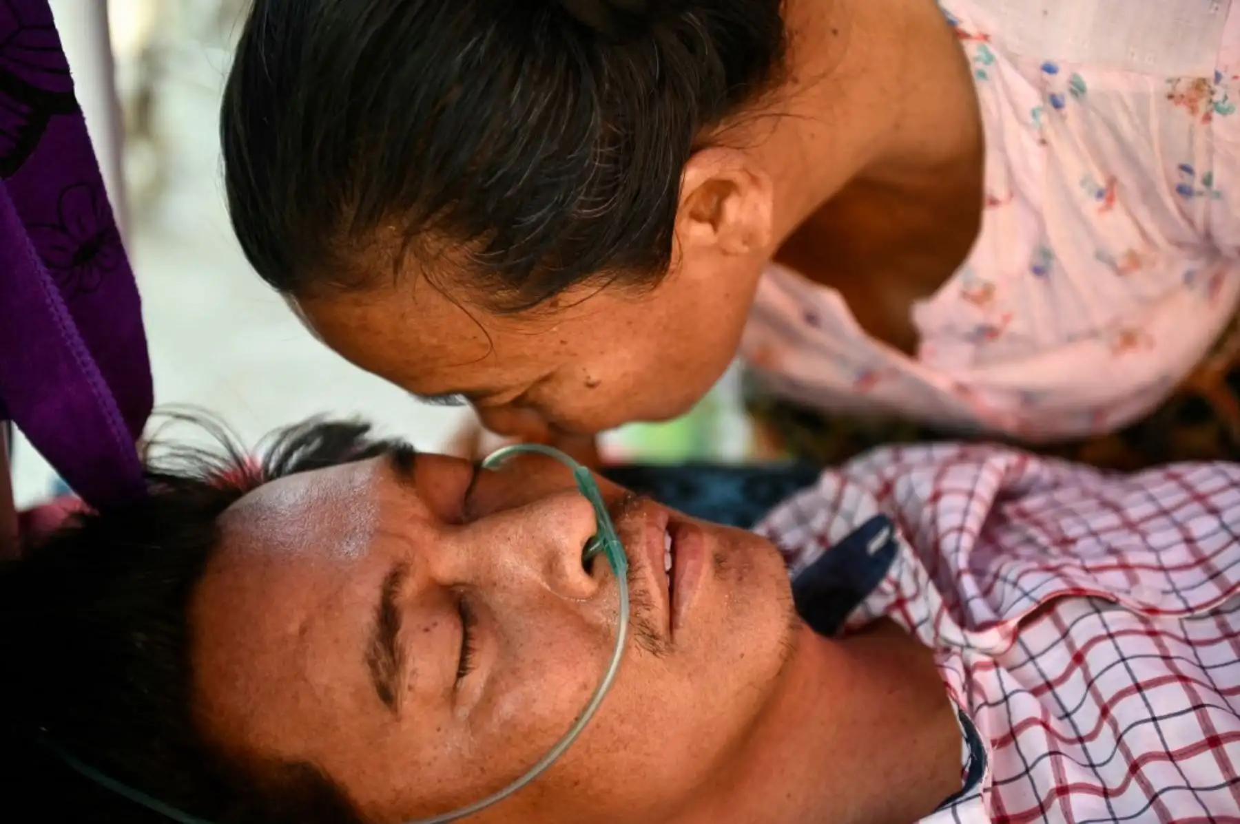 El sobreviviente Tin Maung Htwe recibe consuelo de su hermana mientras descansa en una cama en el recinto de un hospital, recibiendo tratamiento un día después de ser rescatado de las ruinas de un hotel en Sagaing el 3 de abril de 2025, tras el terremoto del 28 de marzo. Enterrado bajo la cama de su hotel durante cinco días entre los escombros, dos cosas le permitieron al maestro Tin Maung Htwe sobrevivir al devastador terremoto de Myanmar: las lecciones de la escuela y su propia orina. Foto: AFP