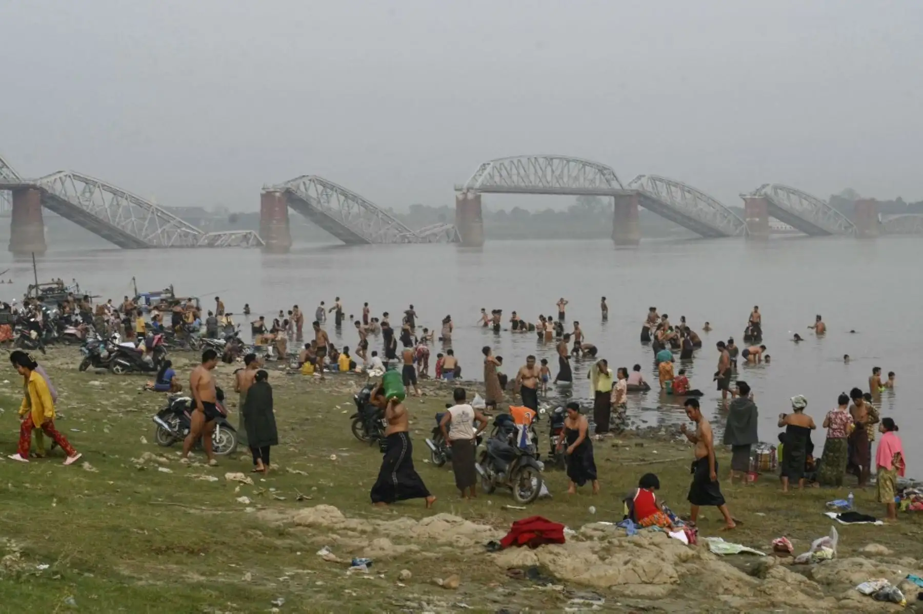 Personas se bañan en el río Irrawaddy frente al derrumbado puente Ava, también conocido como puente Inwa, en Sagaing, mientras zonas residenciales permanecen sin electricidad ni agua. Foto: AFP