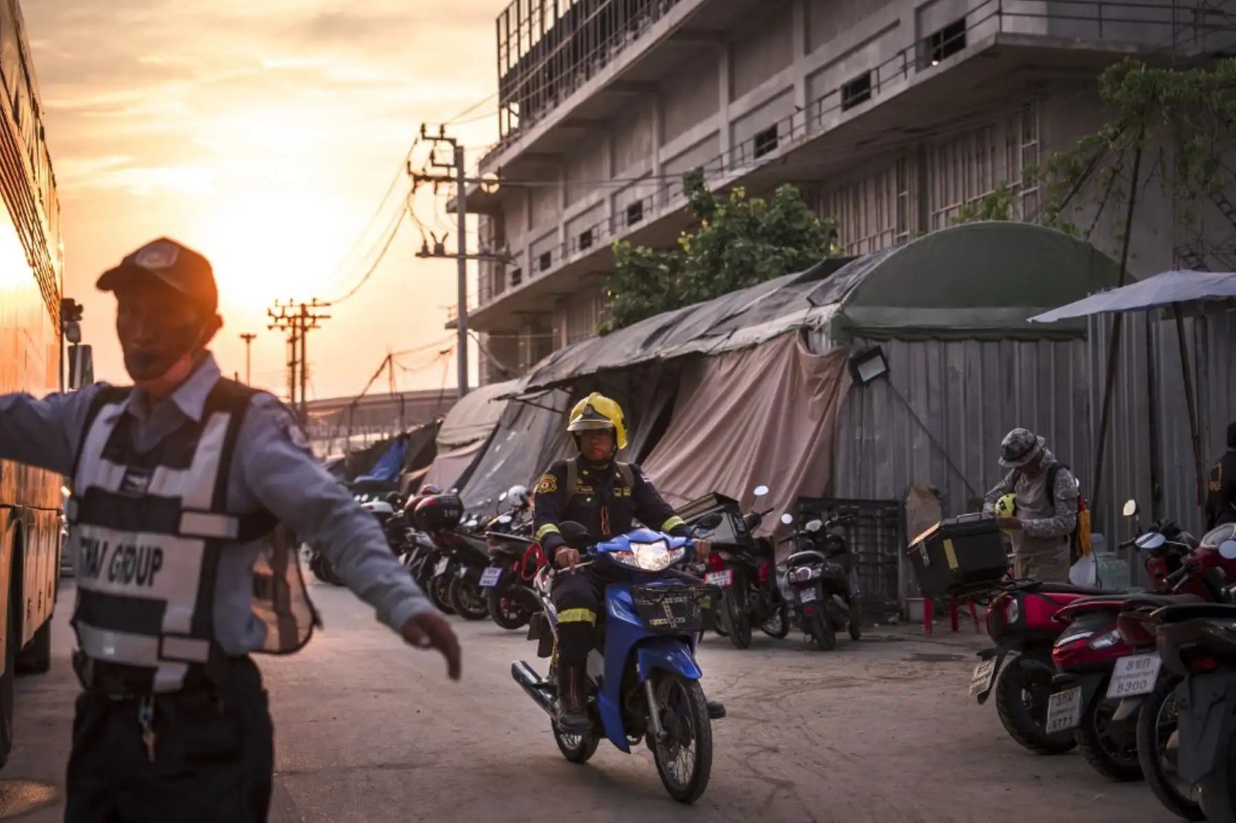 Un oficial conduce una motocicleta al anochecer en el lugar del derrumbe de un edificio en construcción en Bangkok. Foto: AFP