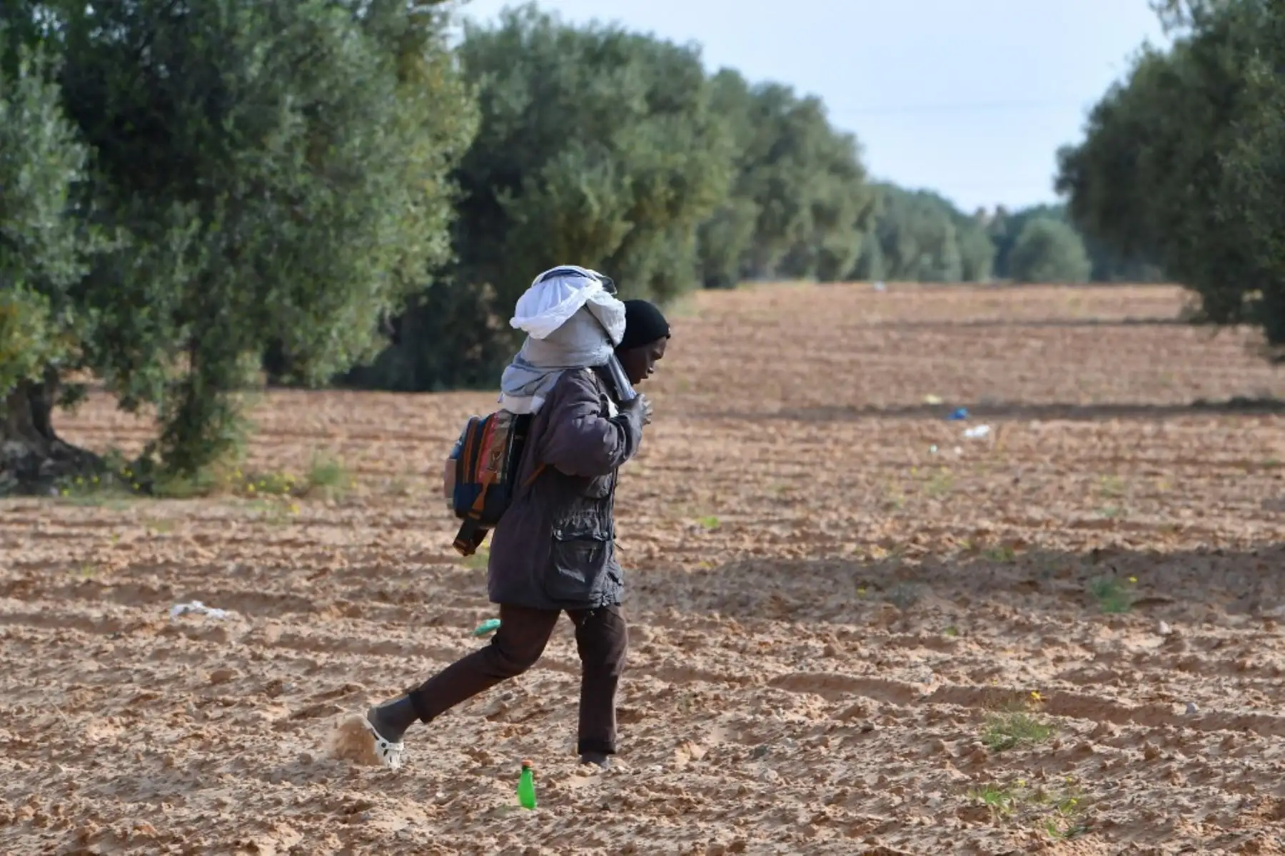 Un migrante carga con sus pertenencias al salir de un campamento para migrantes indocumentados en Al-Amra, a las afueras de la ciudad portuaria tunecina de Sfax, el 5 de abril de 2025, después de que las autoridades comenzaran a desmantelar el campamento. Túnez desmanteló el viernes campamentos que albergaban a miles de migrantes indocumentados del África subsahariana. Foto: AFP