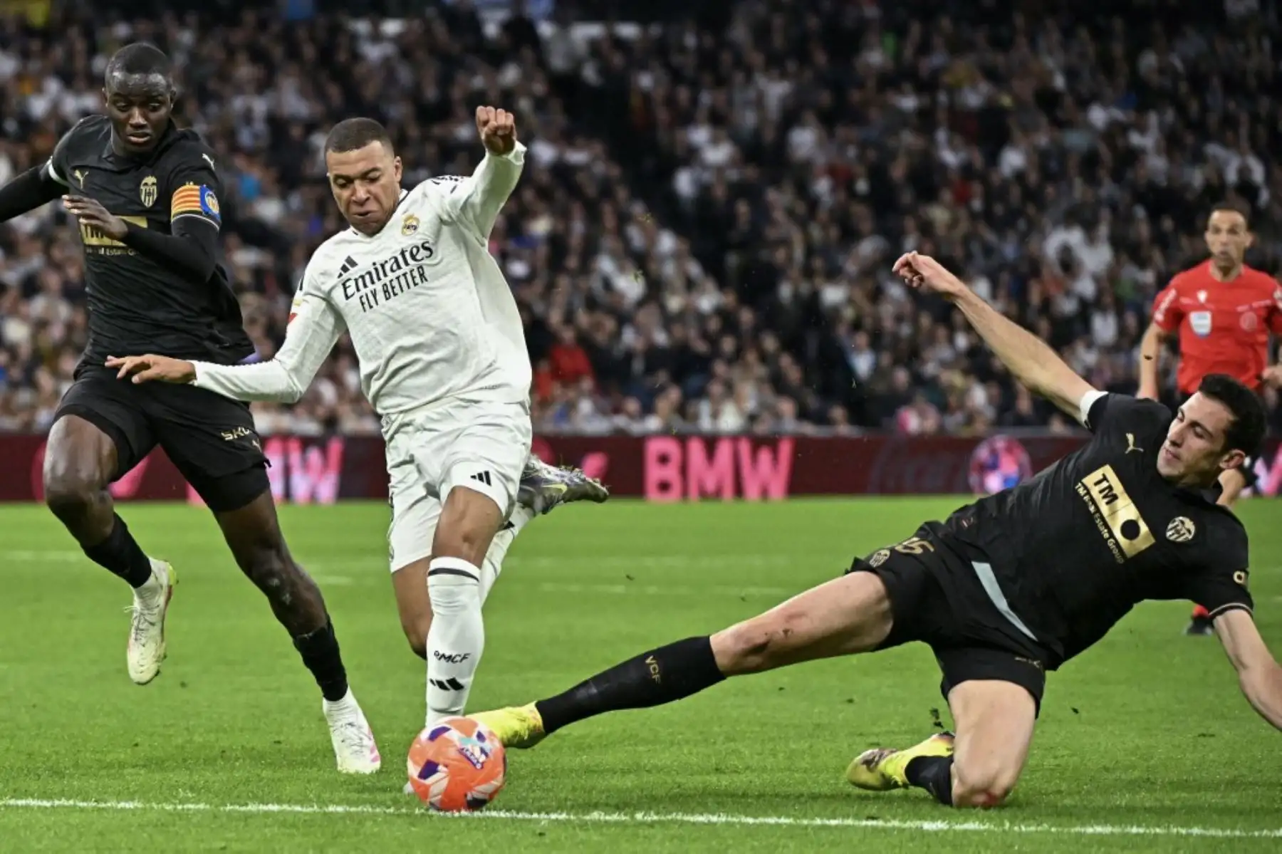 El delantero francés del Real Madrid, Kylian Mbappé, es desafiado por el mediocampista español César Tárrega y el defensor guineano, Mouctar Diakhaby, ambos del Valencia, durante el partido de fútbol de La Liga de España entre el Real Madrid CF y el Valencia CF en el estadio Santiago Bernabéu en Madrid el 5 de abril de 2025. Foto: AFP