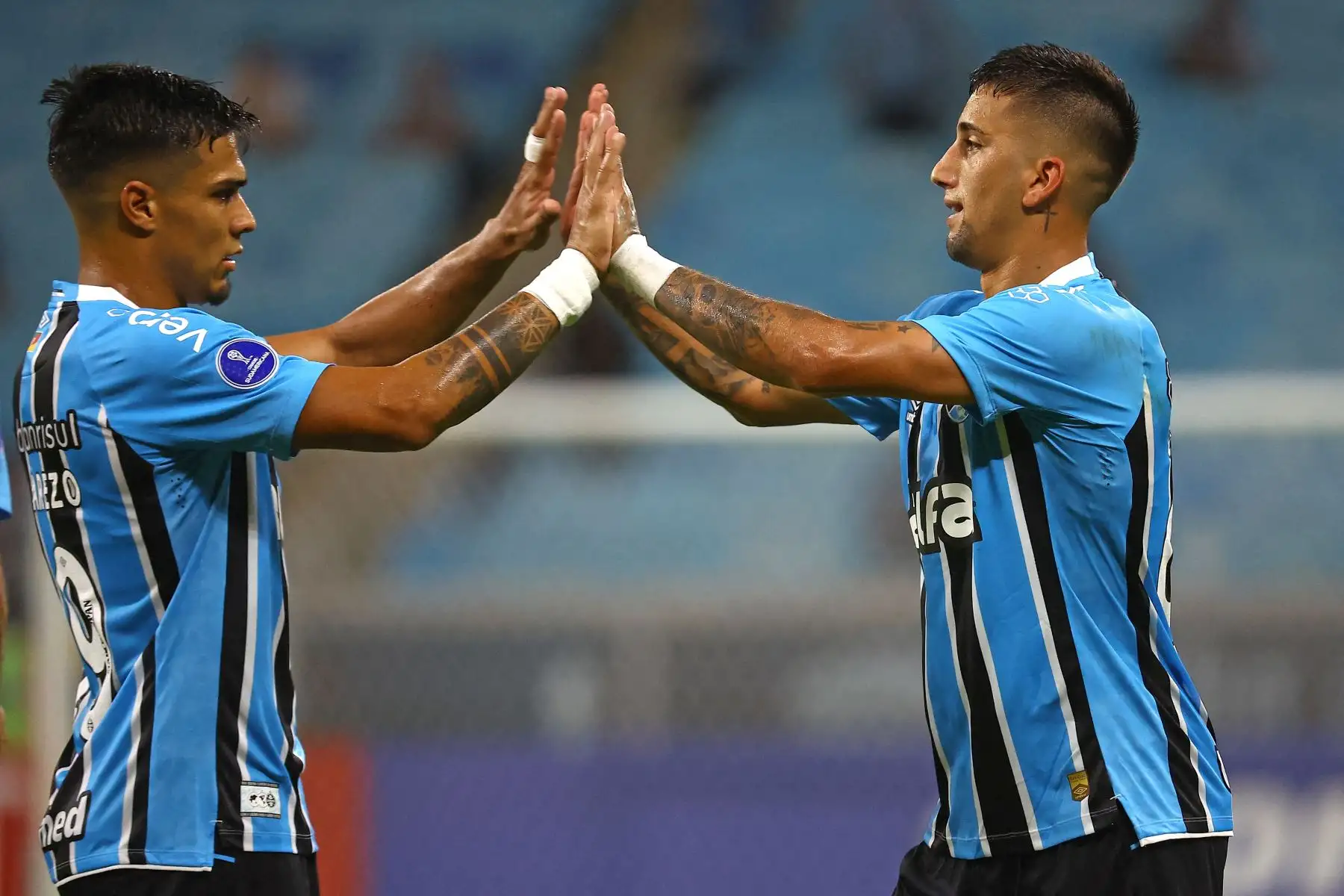 El delantero uruguayo de Gremio, Cristian Olivera, celebra con su compañero de equipo, el delantero uruguayo Matías Arezo, después de marcar el segundo gol de su equipo durante el partido de fútbol de la fase de grupos de la Copa Sudamericana entre Gremio de Brasil y Atlético Grau de Perú en el estadio Arena do Gremio en Porto Alegre, Brasil, el 8 de abril de 2025. Foto: AFP