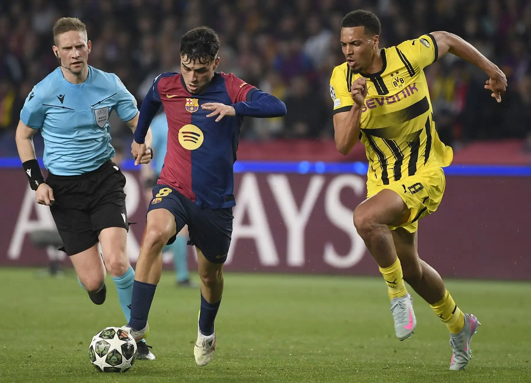 El árbitro noruego Espen Eskas observa al centrocampista español del Barcelona Pedri y al centrocampista alemán  del Borussia Dortmund Felix Nmecha  durante el partido de ida de los cuartos de final de la UEFA Champions League entre el FC Barcelona y el BVB Borussia Dortmund. AFP