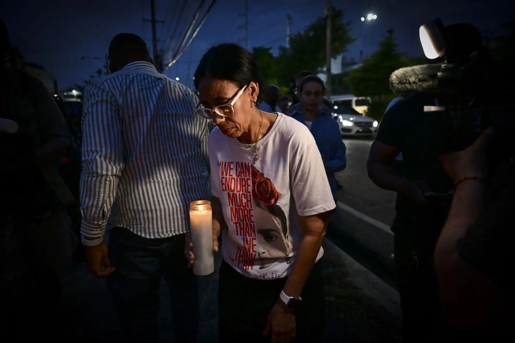 Una mujer sostiene una vela mientras amigos y familiares rinden homenaje a las víctimas frente a la discoteca Jet Set en Santo Domingo. AFP