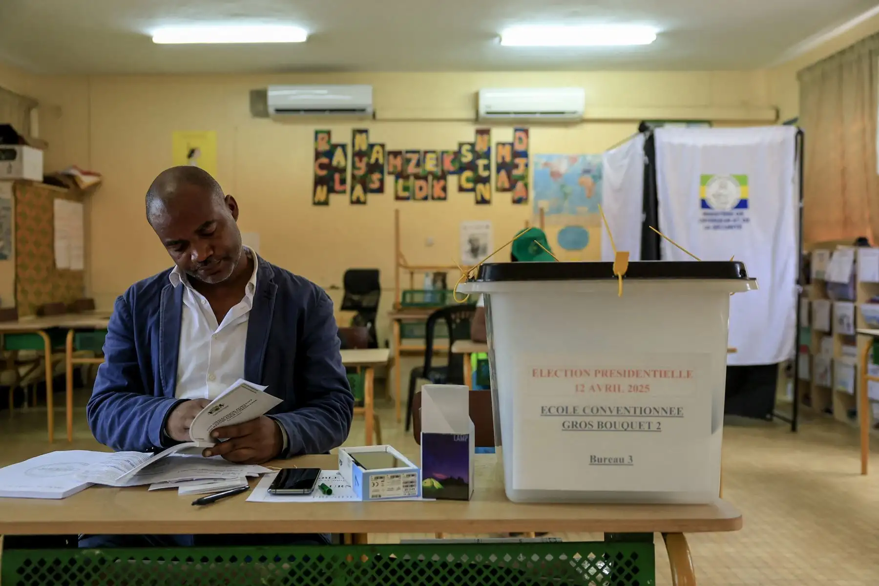 Un funcionario electoral lee un libro con instrucciones en el colegio electoral Gros Bouquet 2 de Libreville el 12 de abril de 2025, durante las elecciones presidenciales de Gabón, las primeras tras el golpe de Estado del 2023. Foto: AFP