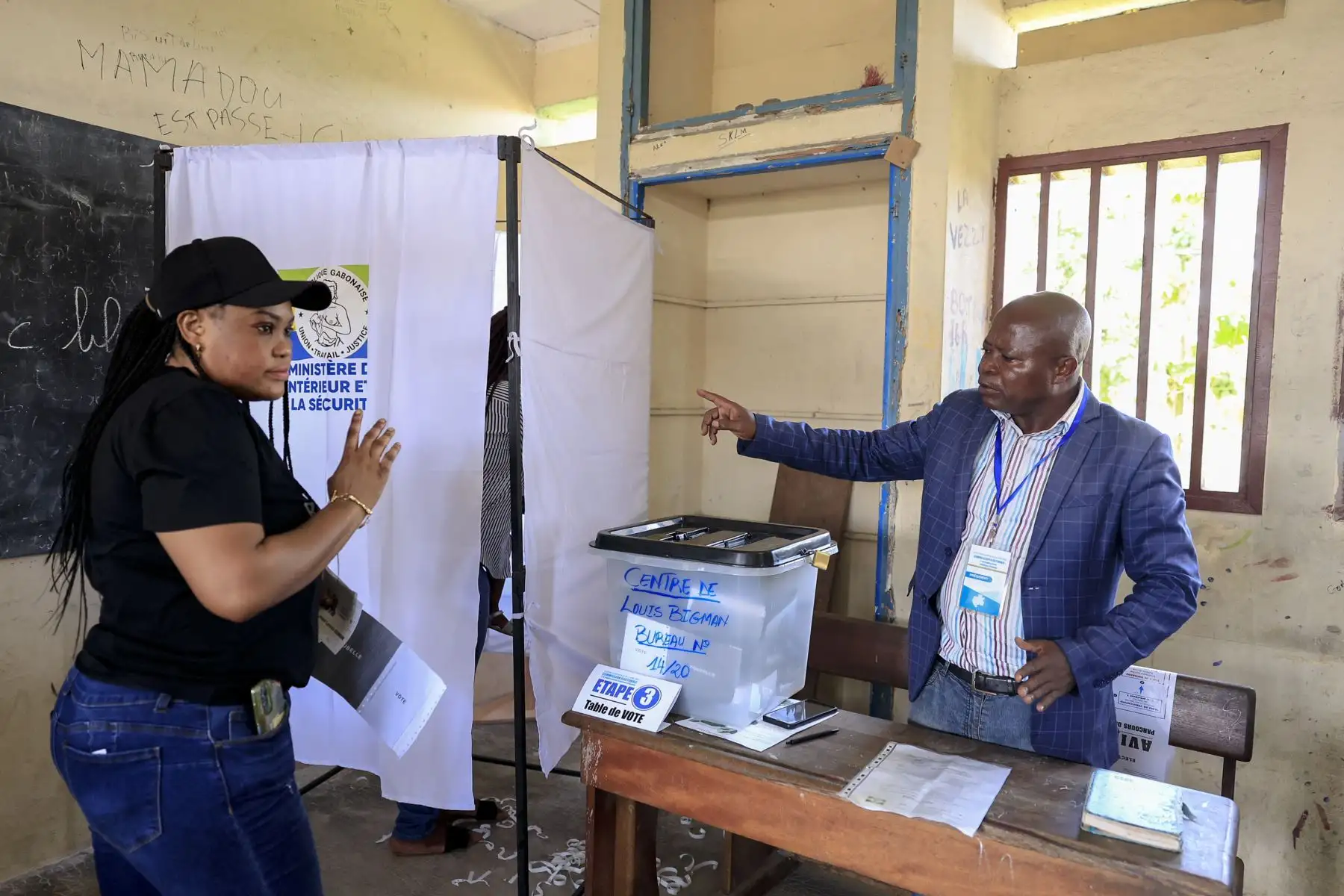 Un funcionario electoral le da unas indicaciones a una votante en el colegio electoral Centre de Louis Bigman en Libreville el 12 de abril de 2025, durante las elecciones presidenciales de Gabón, las primeras tras el golpe de Estado del 2023. Foto: AFP