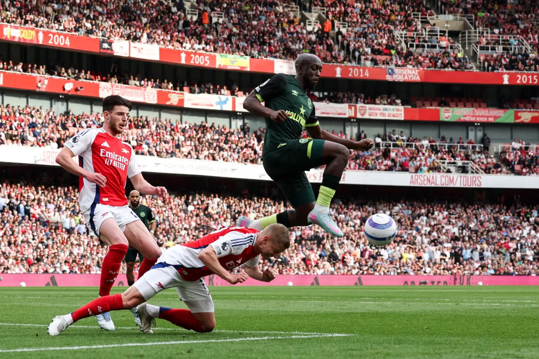 El defensor ucraniano del Arsenal, Oleksandr Zinchenko, cabecea el balón mientras el delantero de la República Democrática del Congo nacido en Francia del Brentford, Yoane Wissa, salta para controlarlo junto al mediocampista inglés del Arsenal, Declan Rice, durante el partido de fútbol de la Premier League inglesa entre Arsenal y Brentford en el Emirates Stadium en Londres el 12 de abril de 2025. Foto: AFP