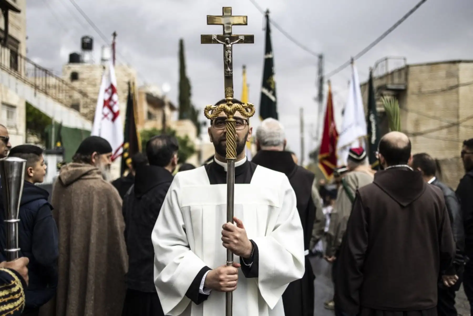 Un sacerdote sostiene una cruz mientras los cristianos marchan por una calle durante la tradicional procesión del Domingo de Ramos en el Monte de los Olivos en Jerusalén, Israel, el 13 de abril de 2025. Foto: AFP