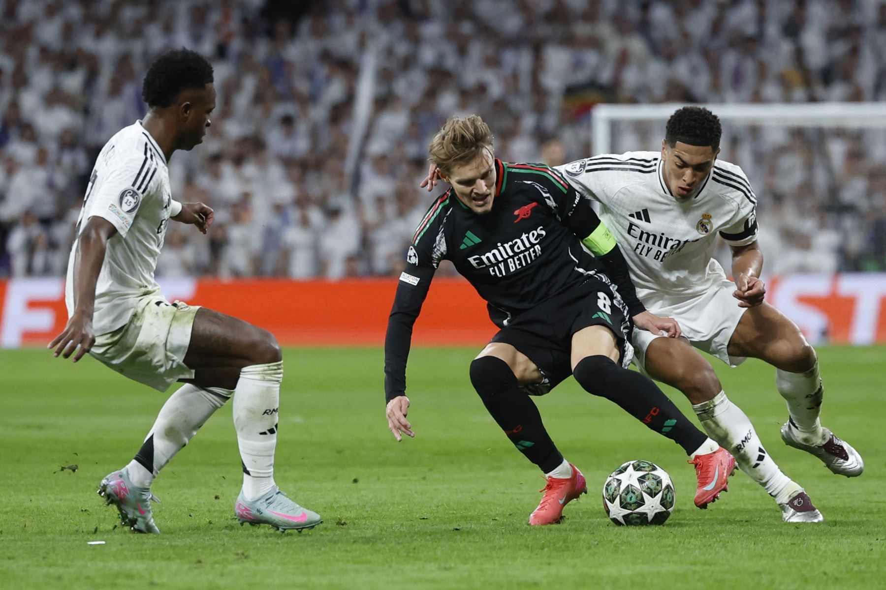 El centrocampista inglés del Real Madrid Jude Bellingham el centrocampista noruego del Arsenal  Martin Odegaard y el delantero brasileño del Real Madrid  Vinicius Junior luchan por el balón durante el partido de vuelta de los cuartos de final de la UEFA Champions League entre el Real Madrid CF y el Arsenal. AFP
