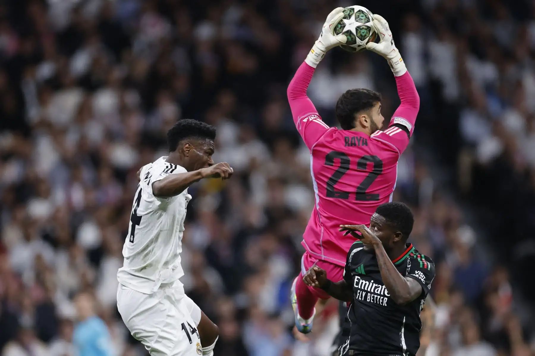 El portero español del Arsenal, David Raya, hace una parada junto al centrocampista francés  del Real Madrid Aurelien Tchouameni y el centrocampista ghanés  del Arsenal, Thomas Partey (R), durante el partido de vuelta de los cuartos de final de la UEFA Champions League entre el Real Madrid CF y el Arsenal. AFP
