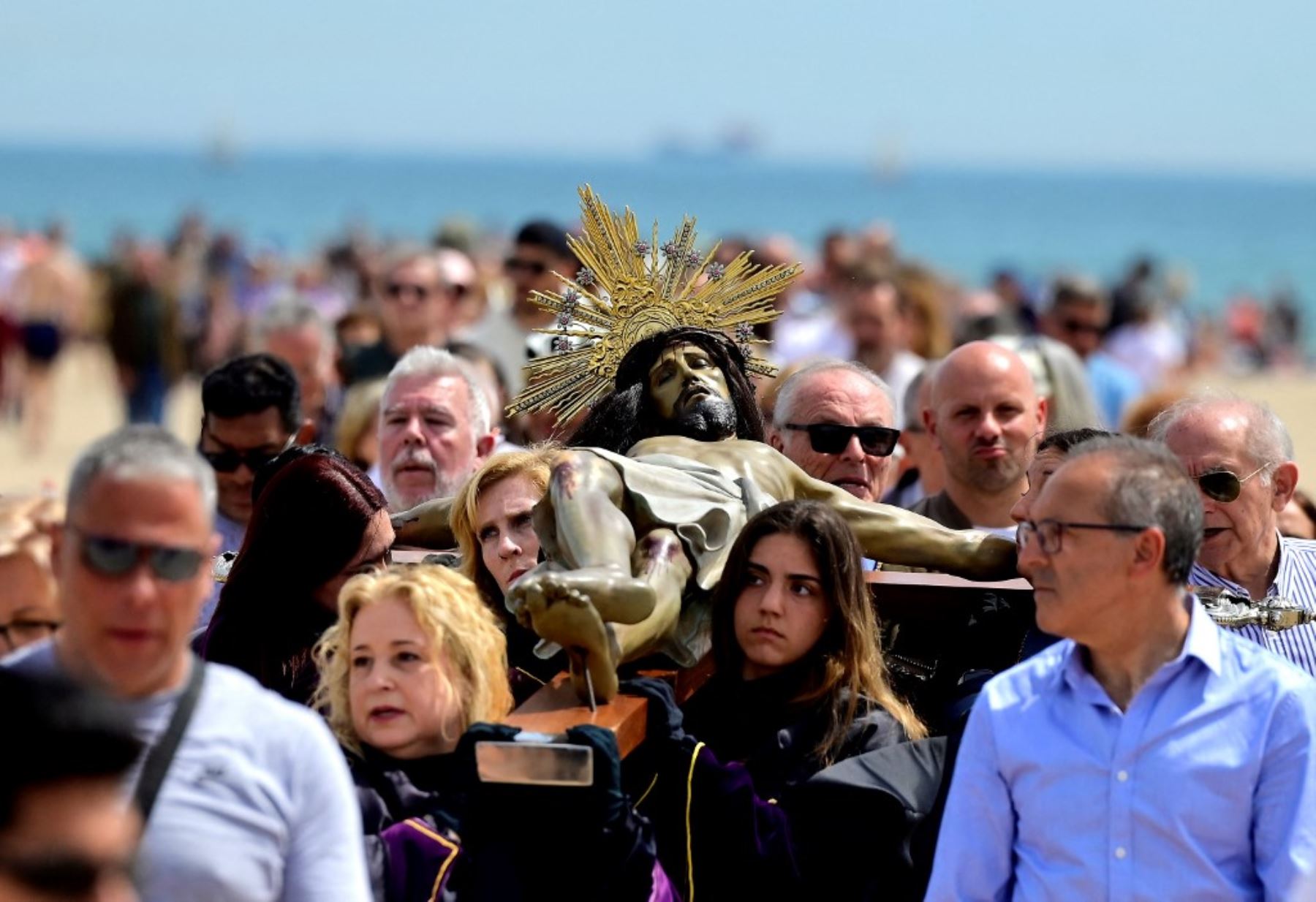 Penitentes de la cofradía del Cristo Salvador y del Amparo portan una cruz durante la procesión de Semana Santa en la playa de Valencia. Foto: AFP