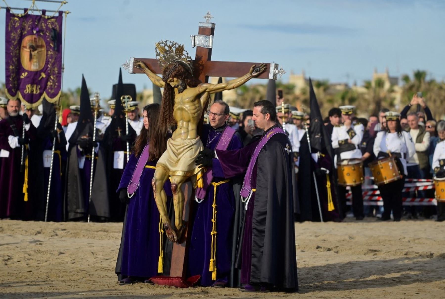 Penitentes llevan una efigie del "Cristo Salvador" en la playa de Valencia durante la Semana Santa el 18 de abril de 2025. Foto: AFP