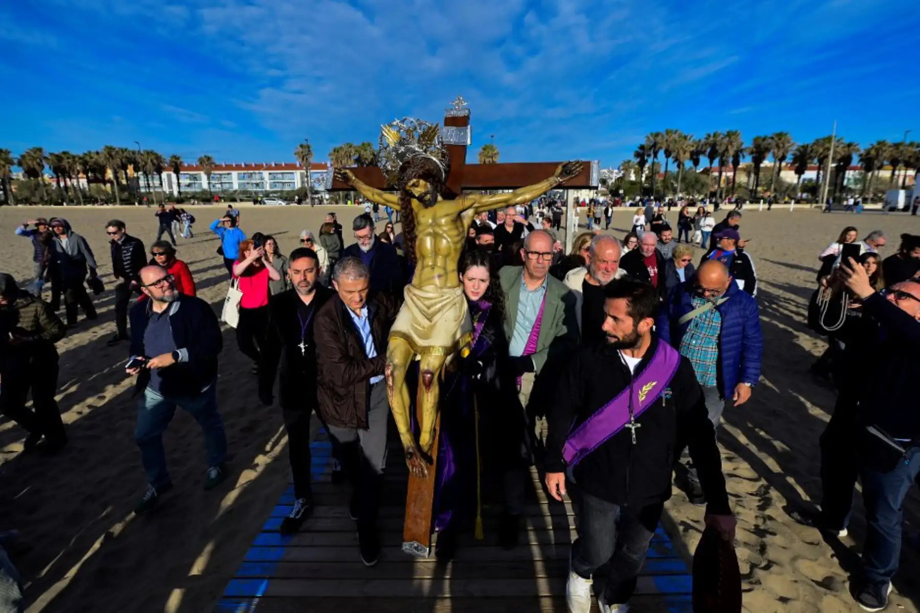 Penitentes llevan una efigie del "Cristo Salvador" en la playa de Valencia durante la Semana Santa el 18 de abril de 2025. Foto: AFP