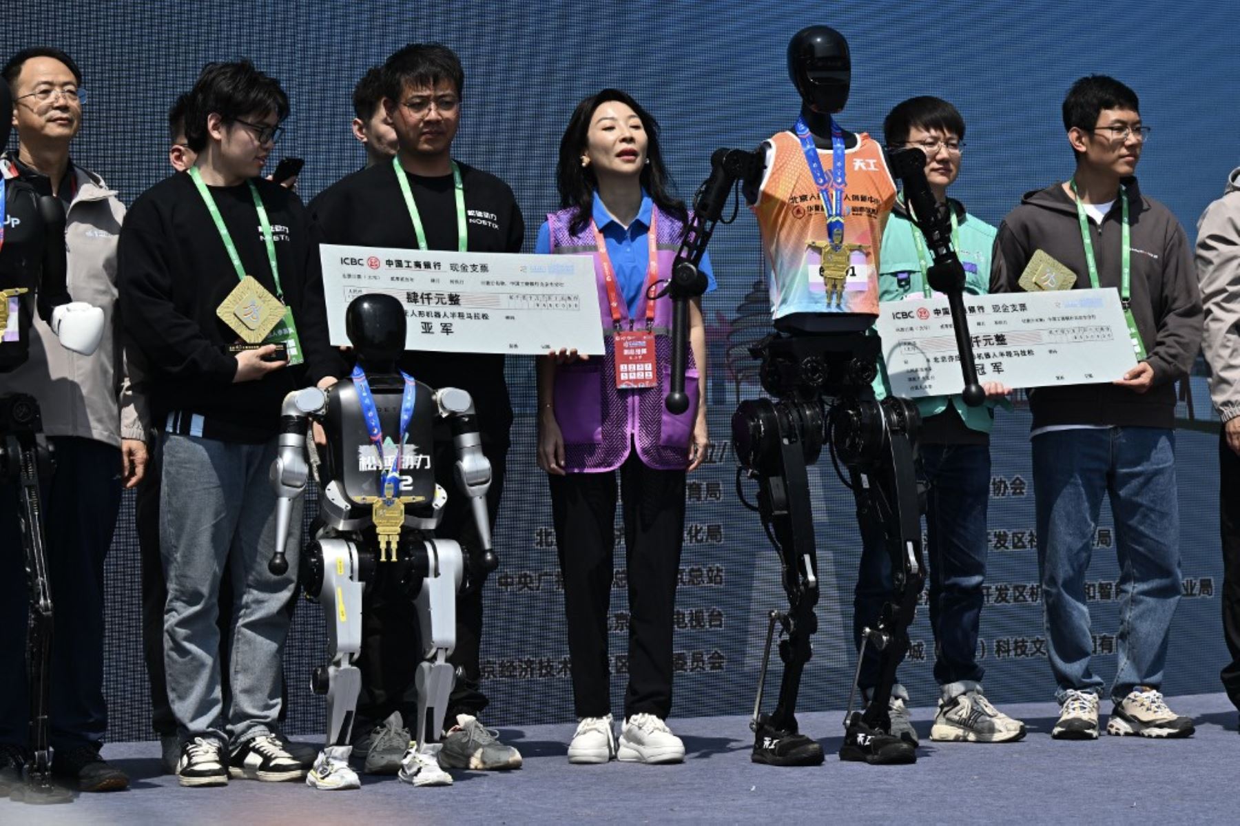Robots y sus ingenieros asisten a la ceremonia de premiación después de la media maratón de robots humanoides en Beijing el 19 de abril de 2025. Decenas de estos robots salieron a las calles de Beijing, uniéndose a miles de participantes humanos en una maratón pionera en el mundo que muestra el impulso de China para liderar la carrera mundial en tecnología de vanguardia. Foto: AFP