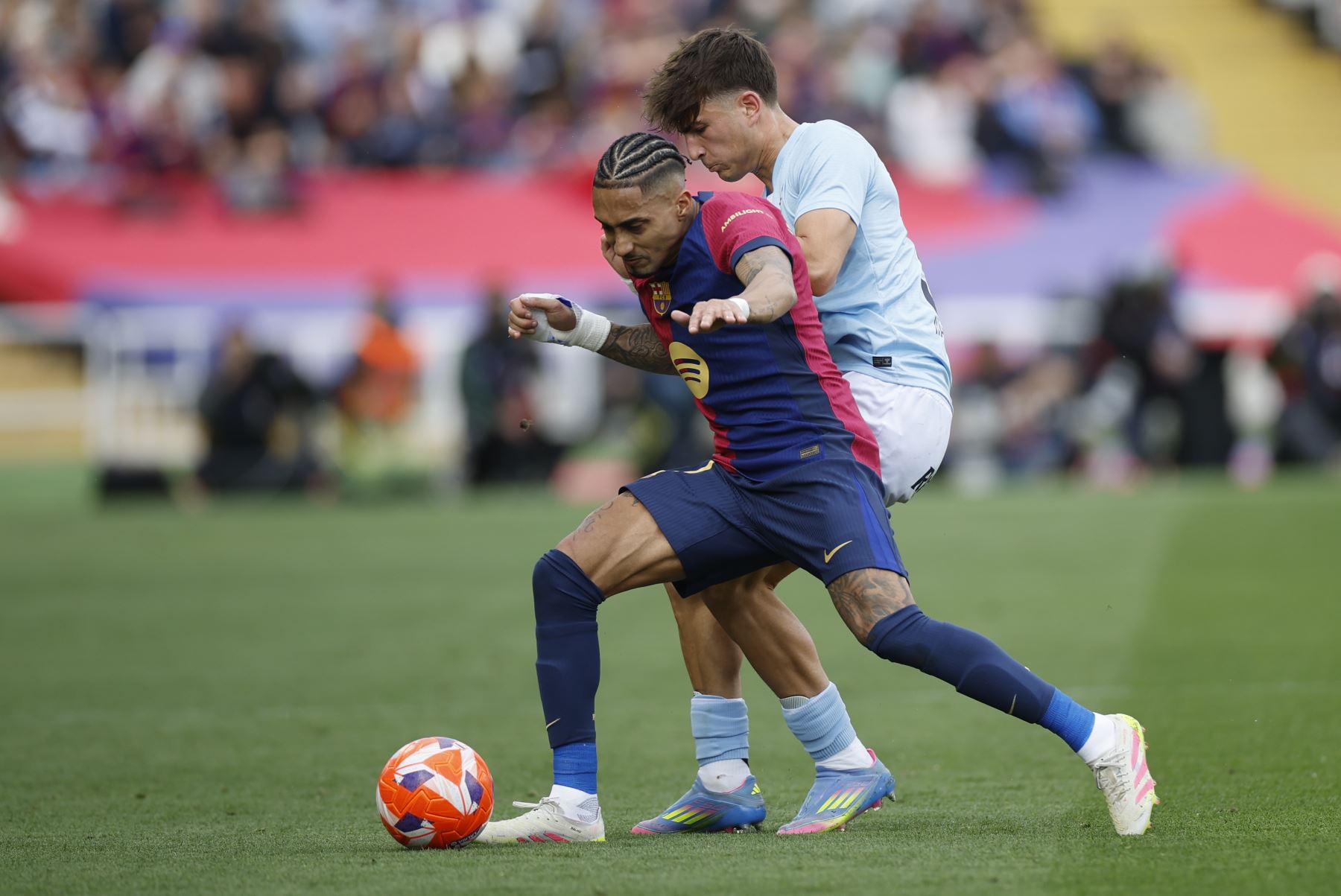 El delantero del FC Barcelona, Raphael Dias Belloli "Raphinha", y el central derecho del Celta de Vigo, Javi Rodríguez, pelean por el balón durante el partido de la jornada 32 de LaLiga EA Sports que FC Barcelona y Celta de Vigo disputan este sábado en el estadio olímpico Lluís Companys en Barcelona. Foto: EFE