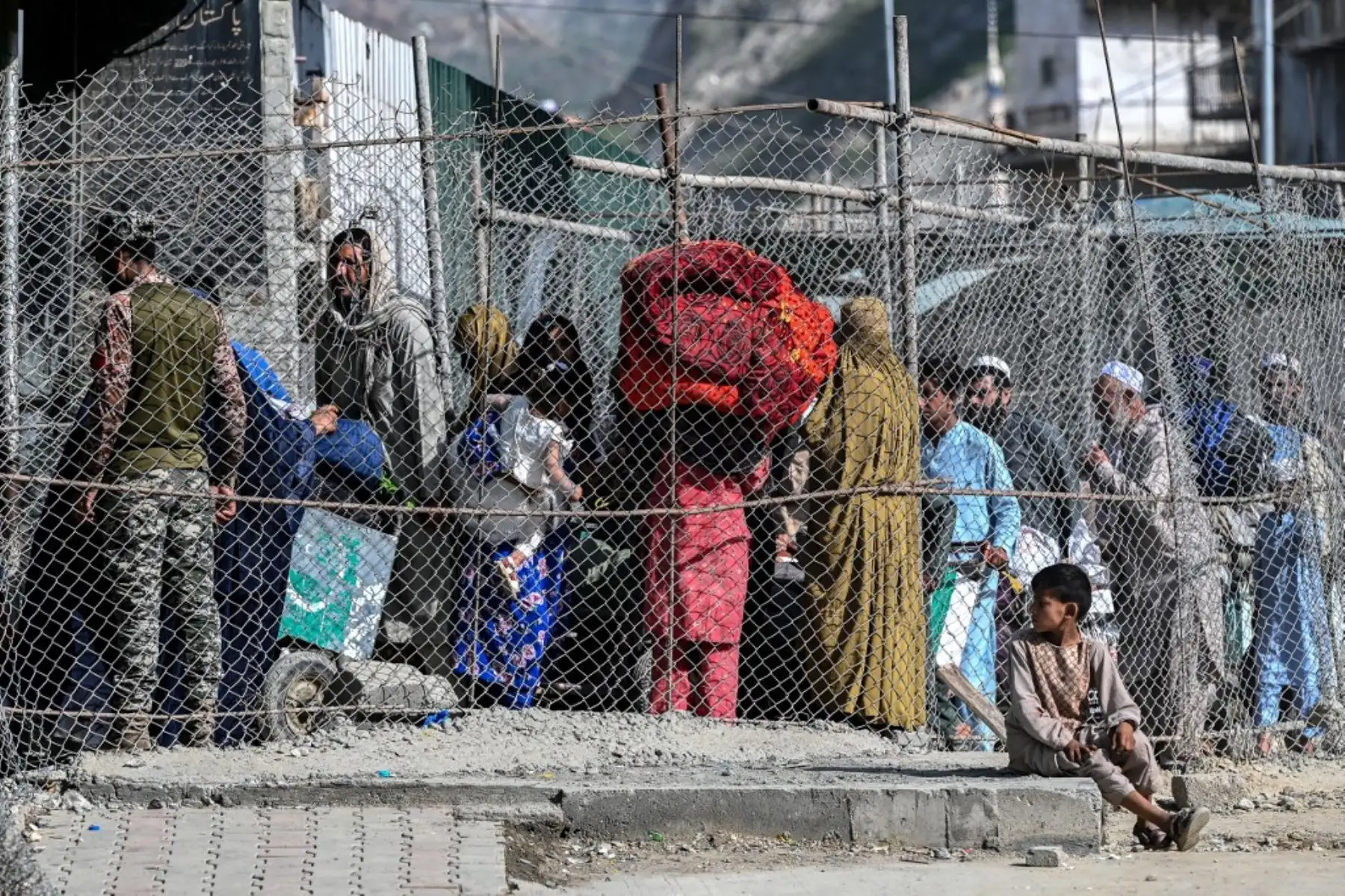 Migrantes afganos caminan por un corredor vallado después de llegar desde Pakistán cerca del punto cero en el cruce fronterizo internacional de Torkham entre Afganistán y Pakistán, en la provincia de Nangarhar, el 20 de abril de 2025. Foto: AFP