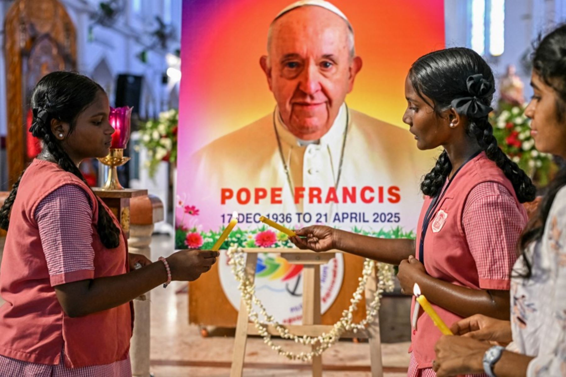 La gente reza ante un retrato del Papa Francisco en una iglesia católica de Chennai en la India el 21 de abril de 2025, tras la noticia de su fallecimiento. Foto: AFP