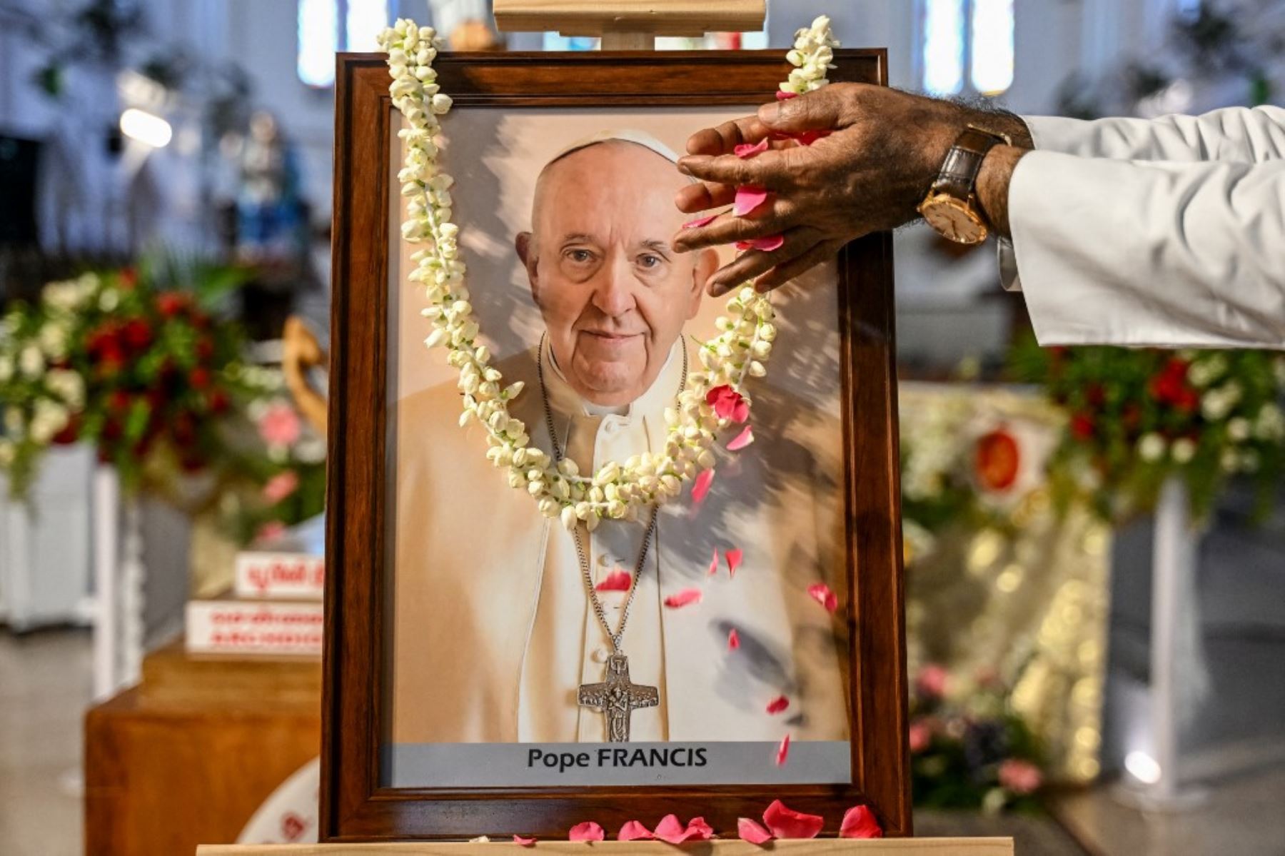 La gente reza ante un retrato del Papa Francisco en una iglesia católica de Chennai en la India el 21 de abril de 2025, tras la noticia de su fallecimiento. Foto: AFP