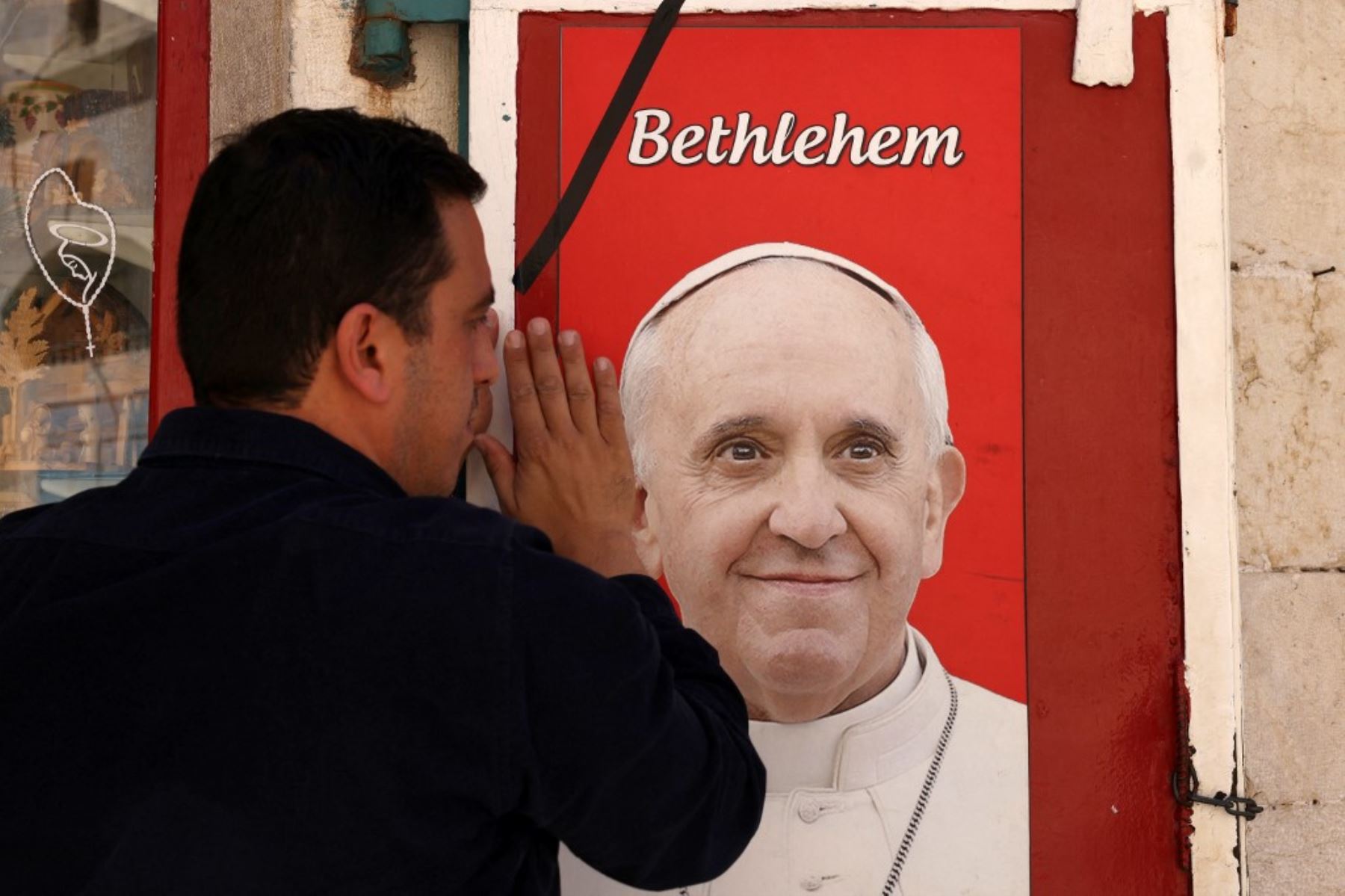 Un hombre toca una imagen del difunto Papa Francisco, expuesta en un cartel frente a una tienda en la ciudad bíblica de Belén, en la Cisjordania ocupada, el 21 de abril de 2025. Foto: AFP